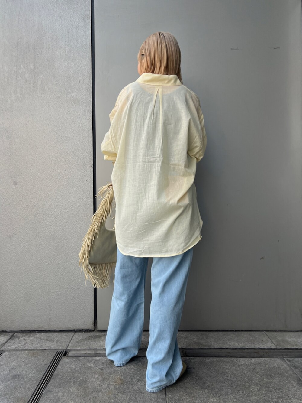 イエロー系のハンドバッグ、ブルー系のデニムパンツ、イエロー系のサンダルを着用したレディースの春コーディネートの4枚目の写真