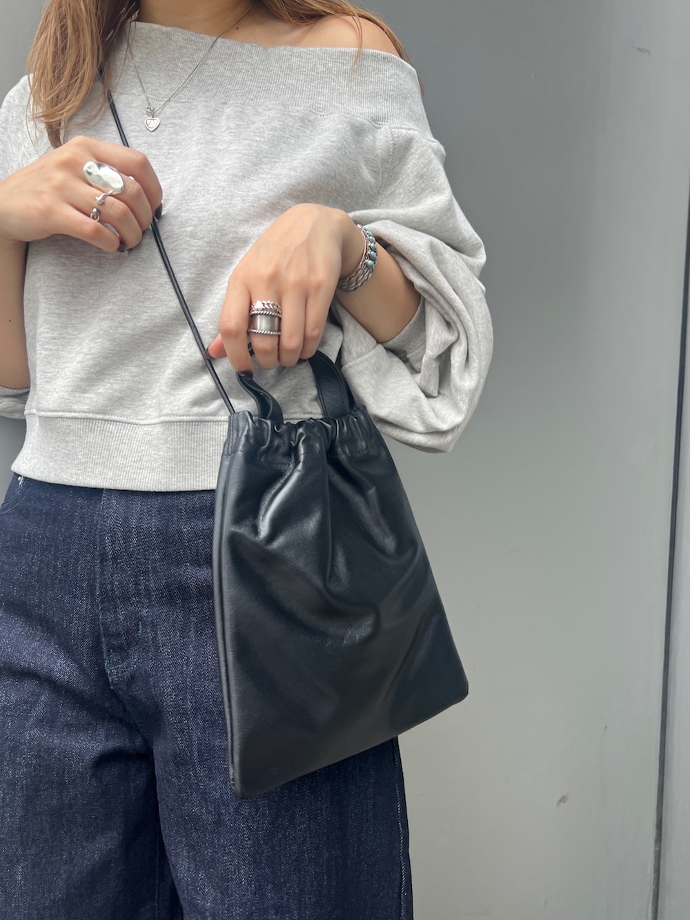 ブルー系のデニムパンツ、グレー系のスウェット、ブラック系のショルダーバッグを着用したレディースの秋コーディネートの6枚目の写真