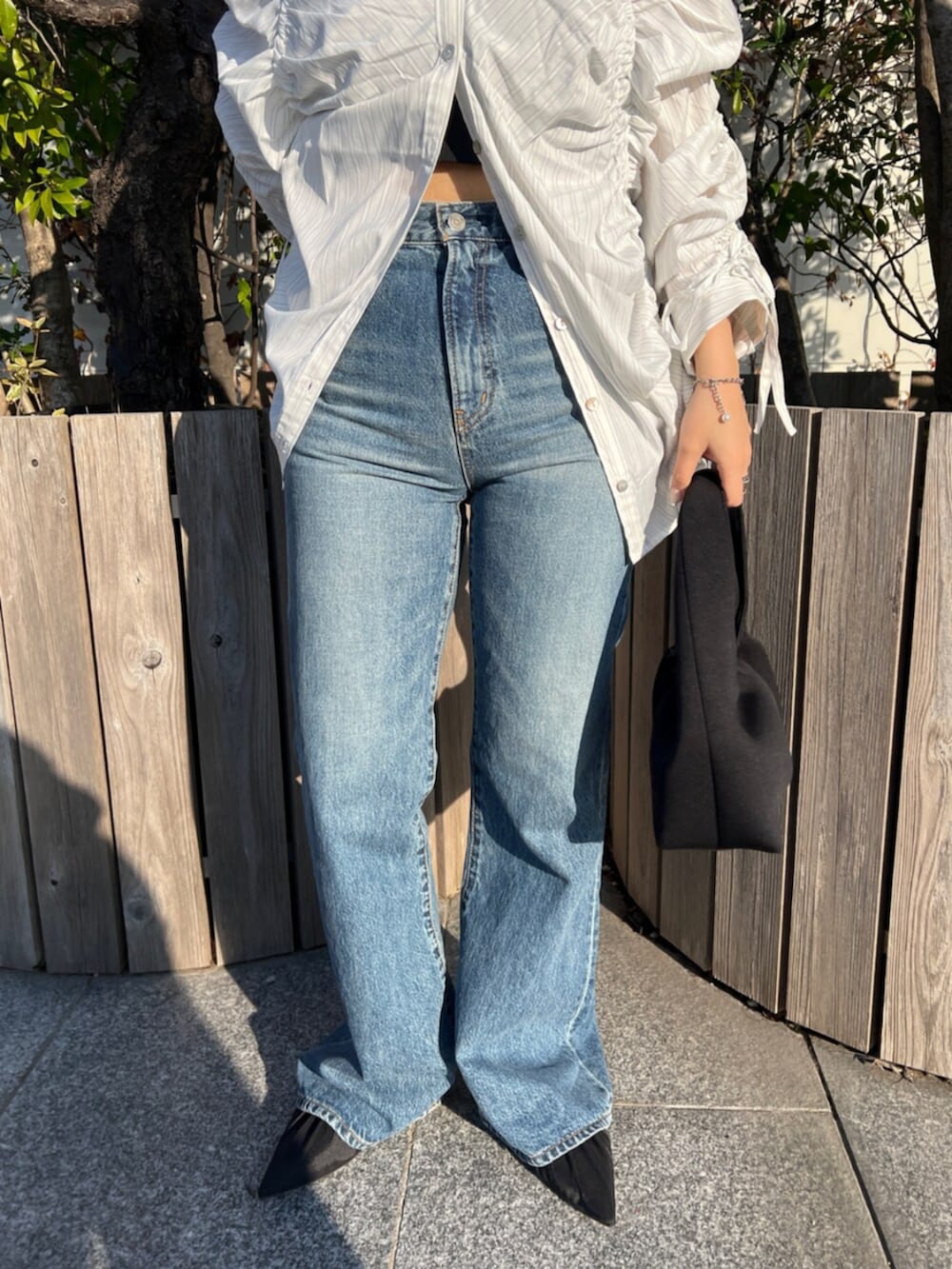 ブラック系のパンプス、ホワイト系のシャツ/ブラウス、ブルー系のデニムパンツを着用したレディースの春コーディネートの4枚目の写真