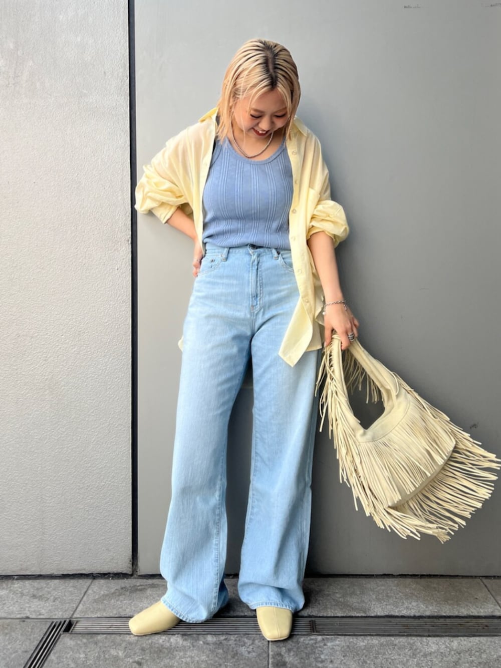 イエロー系のハンドバッグ、ブルー系のデニムパンツ、イエロー系のサンダルを着用したレディースの春コーディネートの2枚目の写真