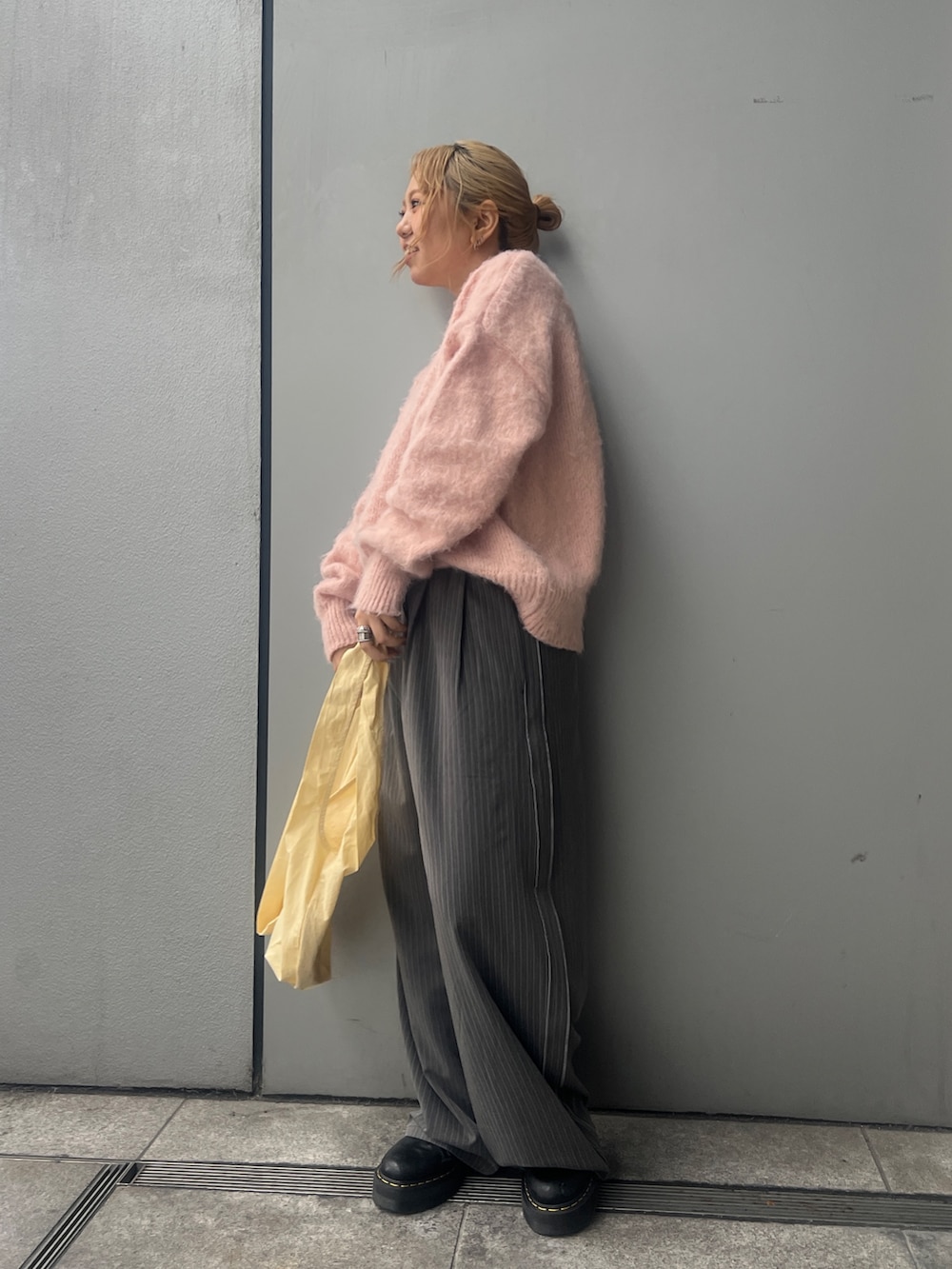 ピンク系のニット/セーター、イエロー系のトートバッグ、グレー系のその他パンツを着用したレディースの冬コーディネートの2枚目の写真