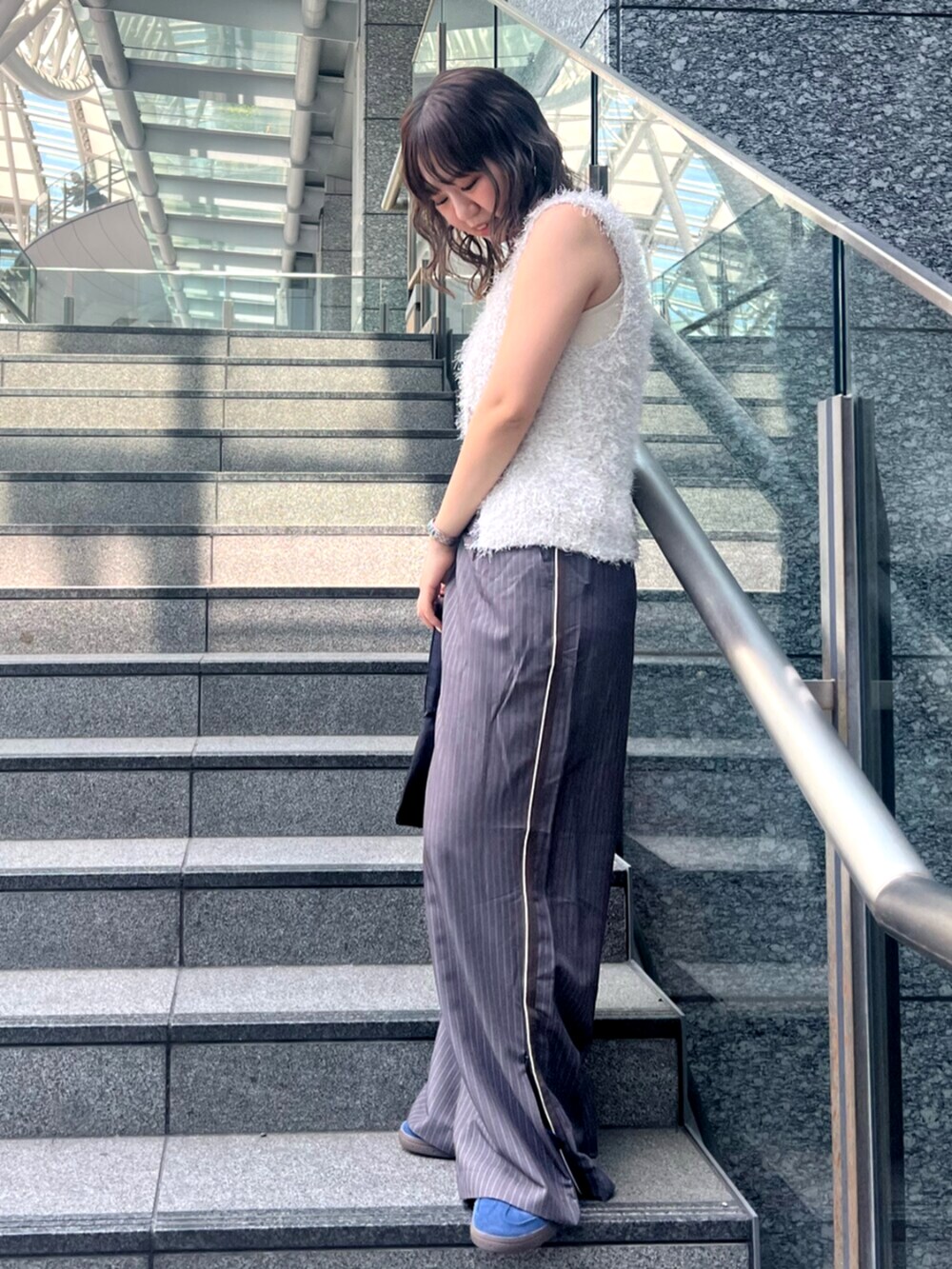 グレー系のその他パンツ、ホワイト系のベスト、ホワイト系のキャミソールを着用したレディースの春コーディネートの2枚目の写真