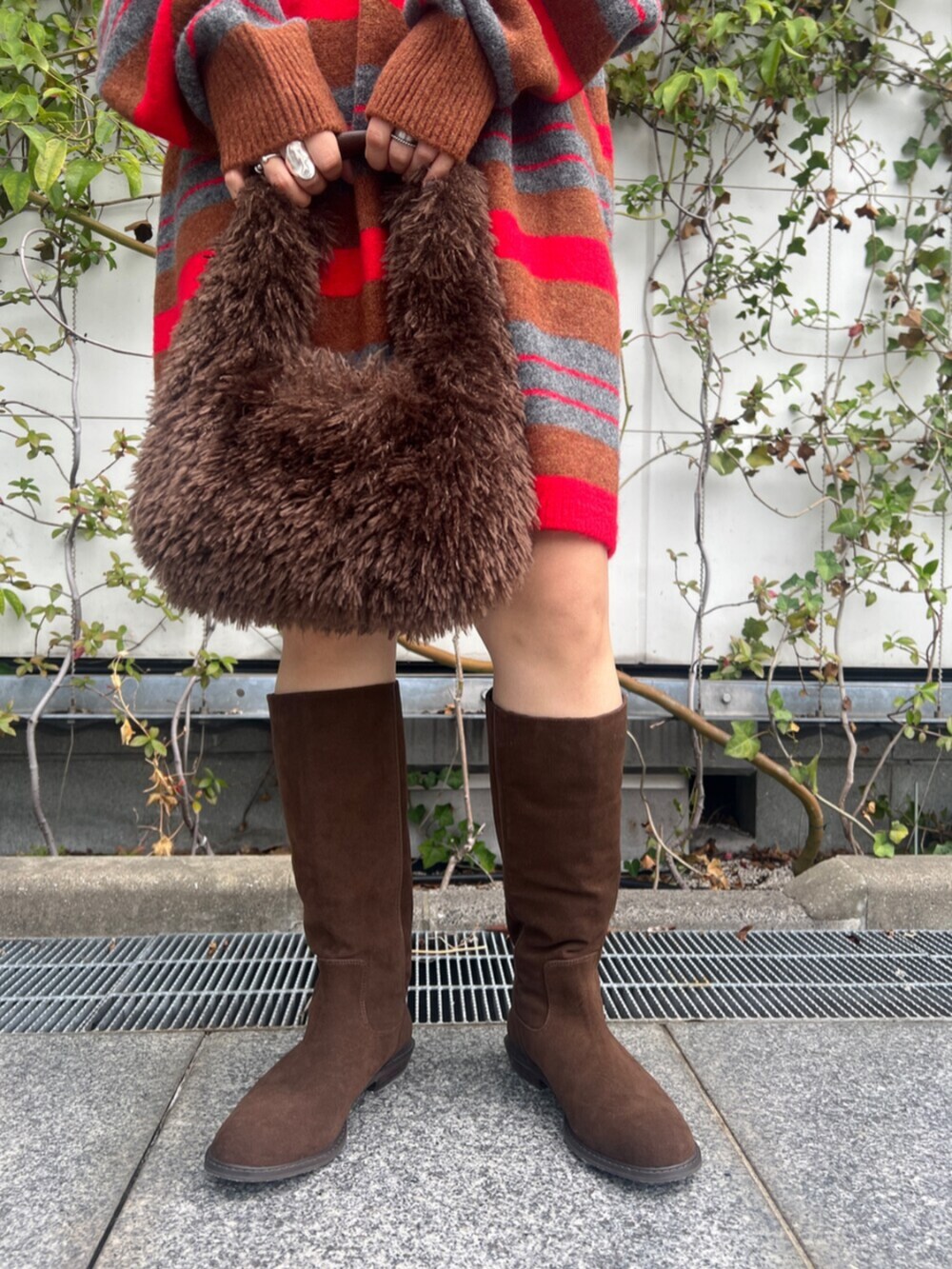 ブラウン系のハンドバッグ、レッド系のニット/セーター、ブラウン系のブーツを着用したレディースの秋コーディネートの6枚目の写真