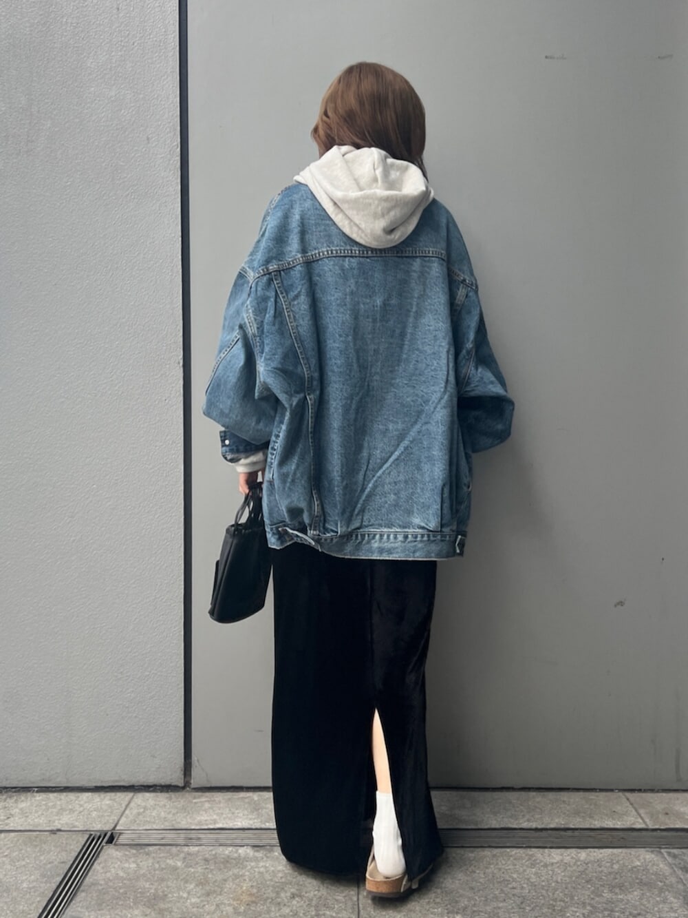 ホワイト系のパーカー、ブルー系のデニムジャケット、ブラック系のスカートを着用したレディースの秋コーディネートの4枚目の写真