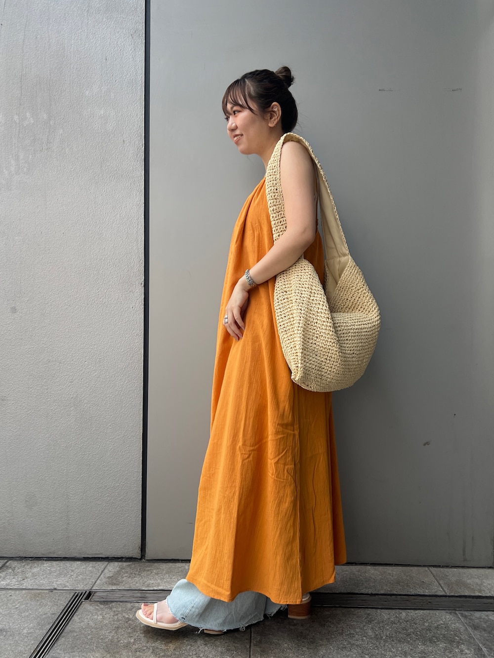 オレンジ系のワンピース、グレー系のタンクトップ、ベージュ系のショルダーバッグを着用したレディースの夏コーディネートの3枚目の写真