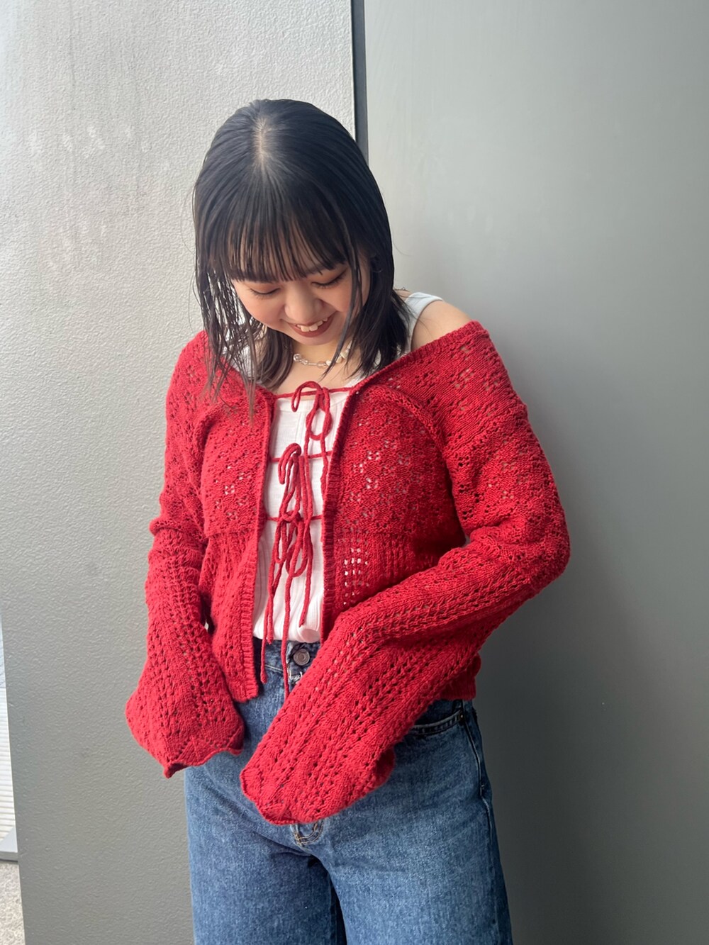 ブルー系のデニムパンツ、レッド系のカーディガン/ボレロ、ホワイト系のタンクトップを着用したレディースの冬コーディネートの4枚目の写真