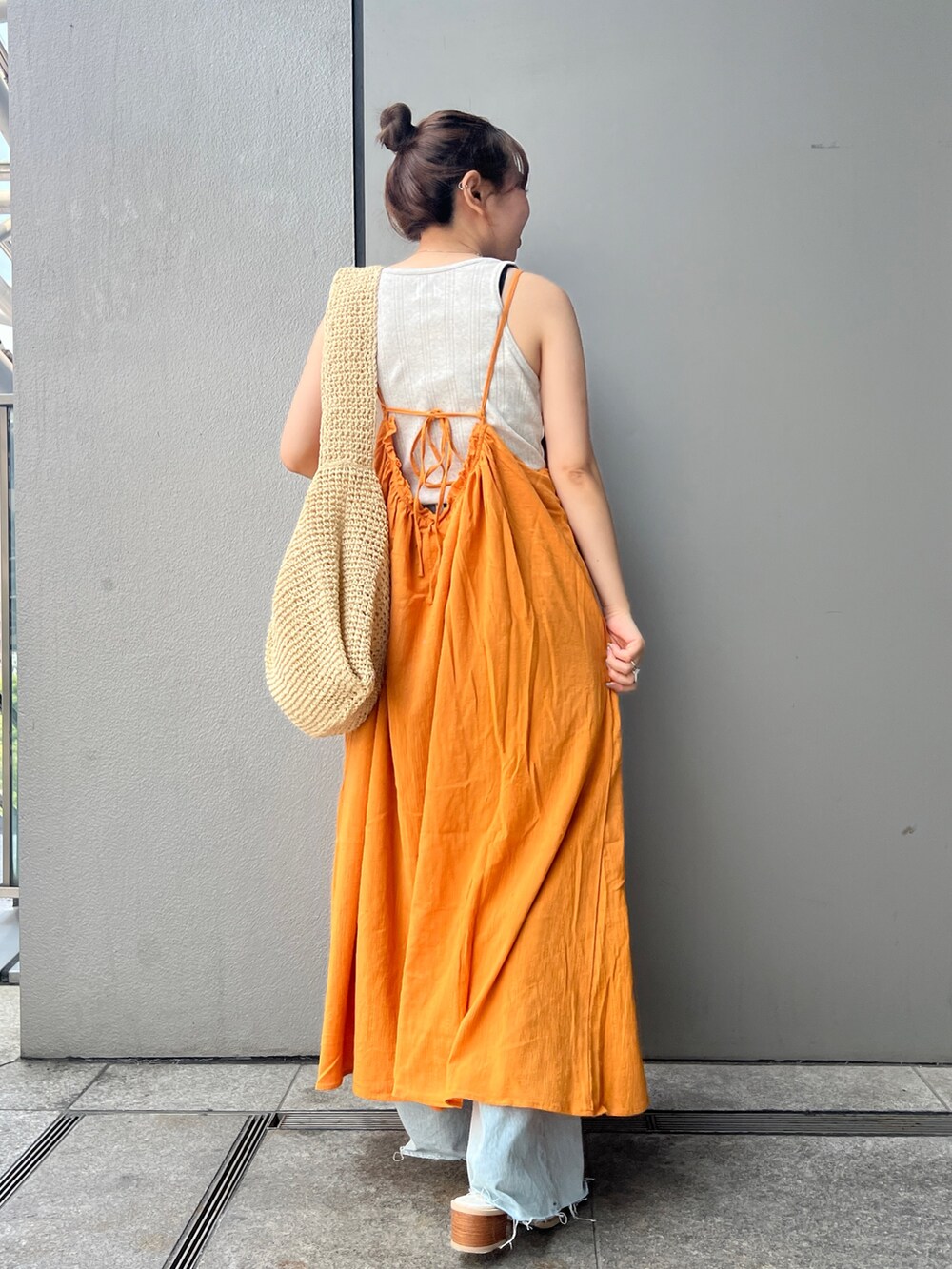 オレンジ系のワンピース、グレー系のタンクトップ、ベージュ系のショルダーバッグを着用したレディースの夏コーディネートの2枚目の写真