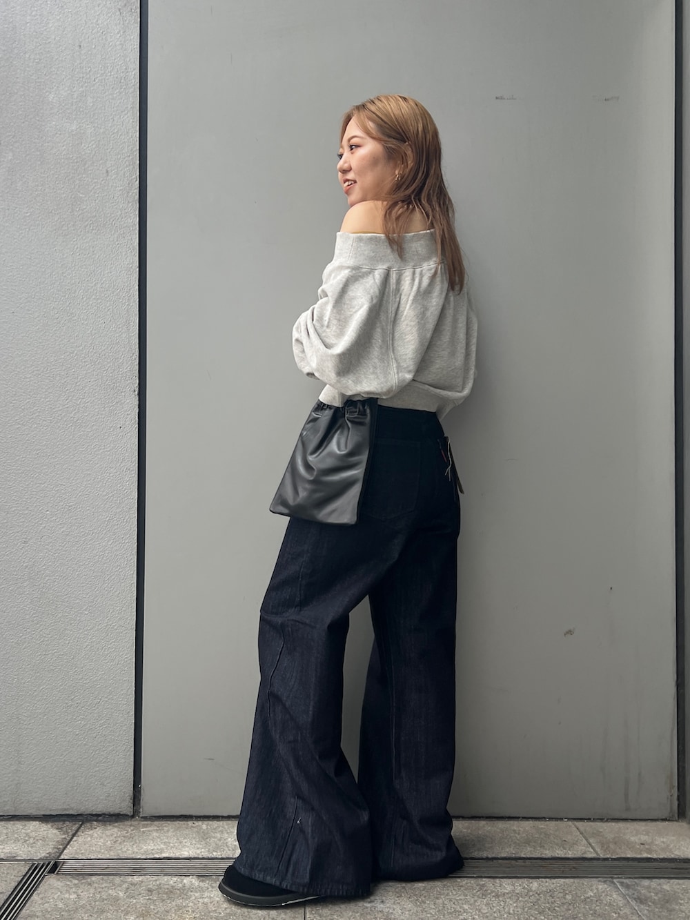 ブルー系のデニムパンツ、グレー系のスウェット、ブラック系のショルダーバッグを着用したレディースの秋コーディネートの2枚目の写真
