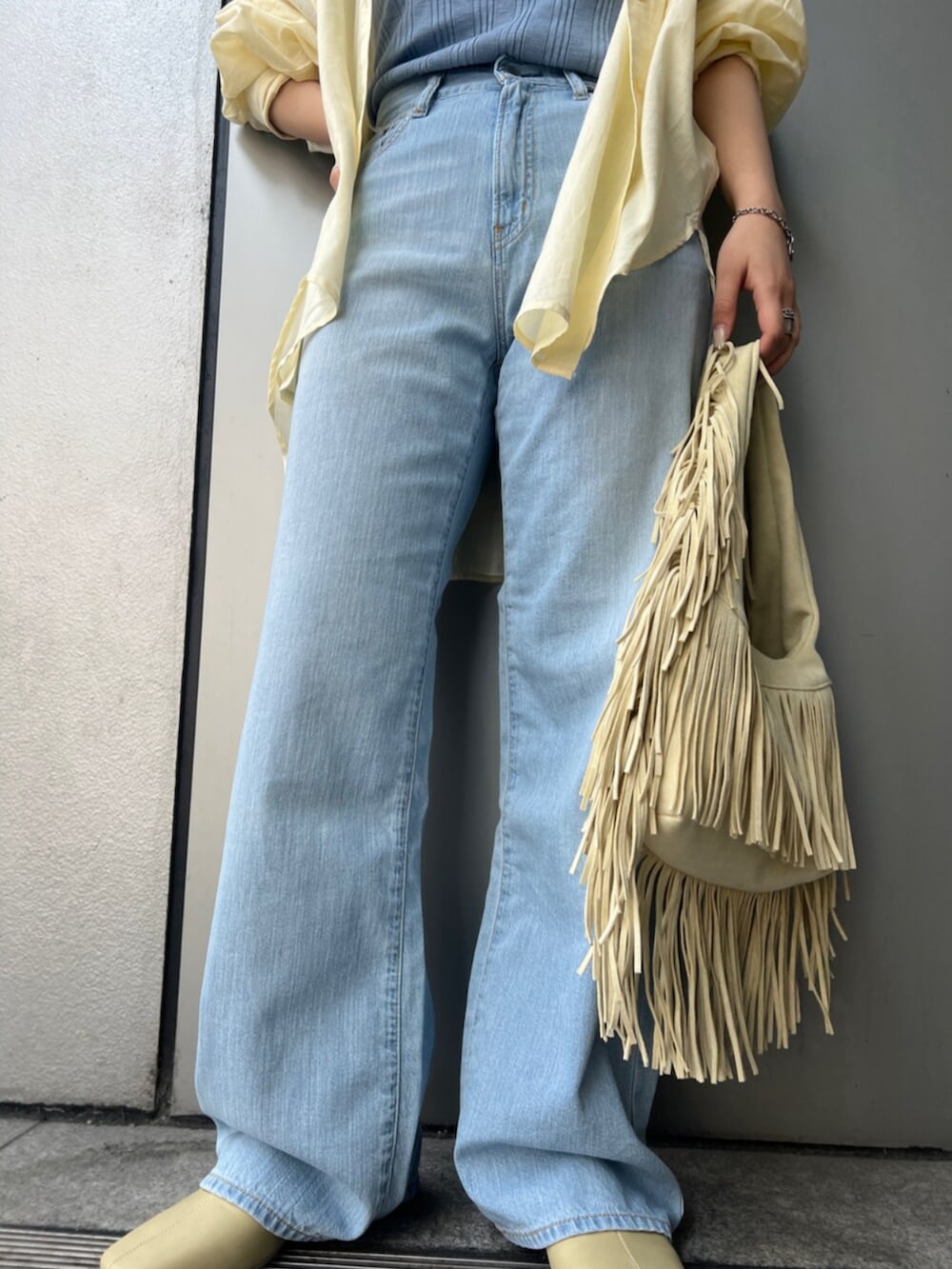 イエロー系のハンドバッグ、ブルー系のデニムパンツ、イエロー系のサンダルを着用したレディースの春コーディネートの5枚目の写真