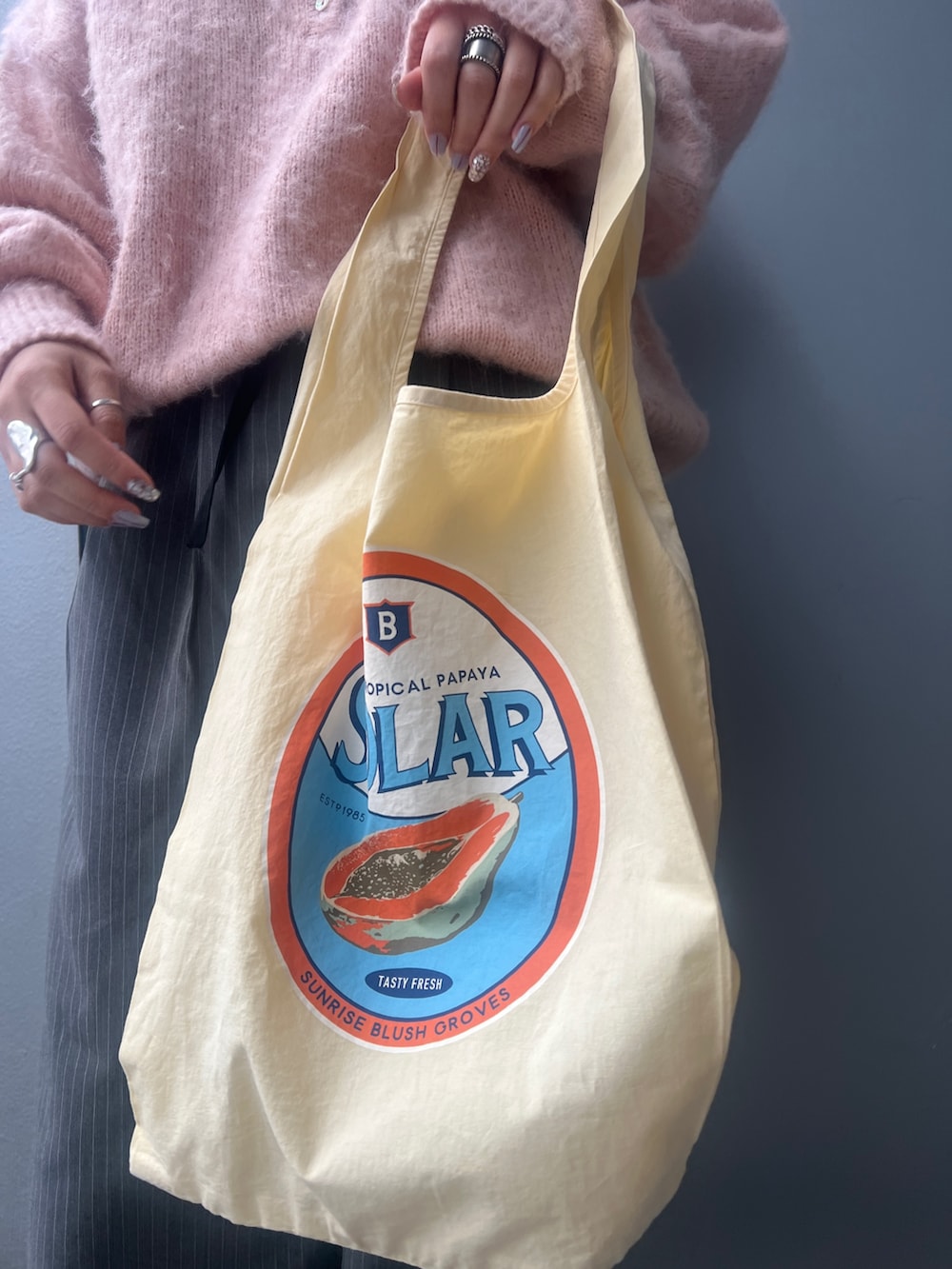 ピンク系のニット/セーター、イエロー系のトートバッグ、グレー系のその他パンツを着用したレディースの冬コーディネートの7枚目の写真