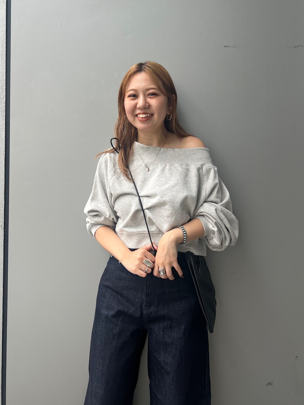 ブルー系のデニムパンツ、グレー系のスウェット、ブラック系のショルダーバッグを着用したレディースの秋コーディネートの4枚目の写真