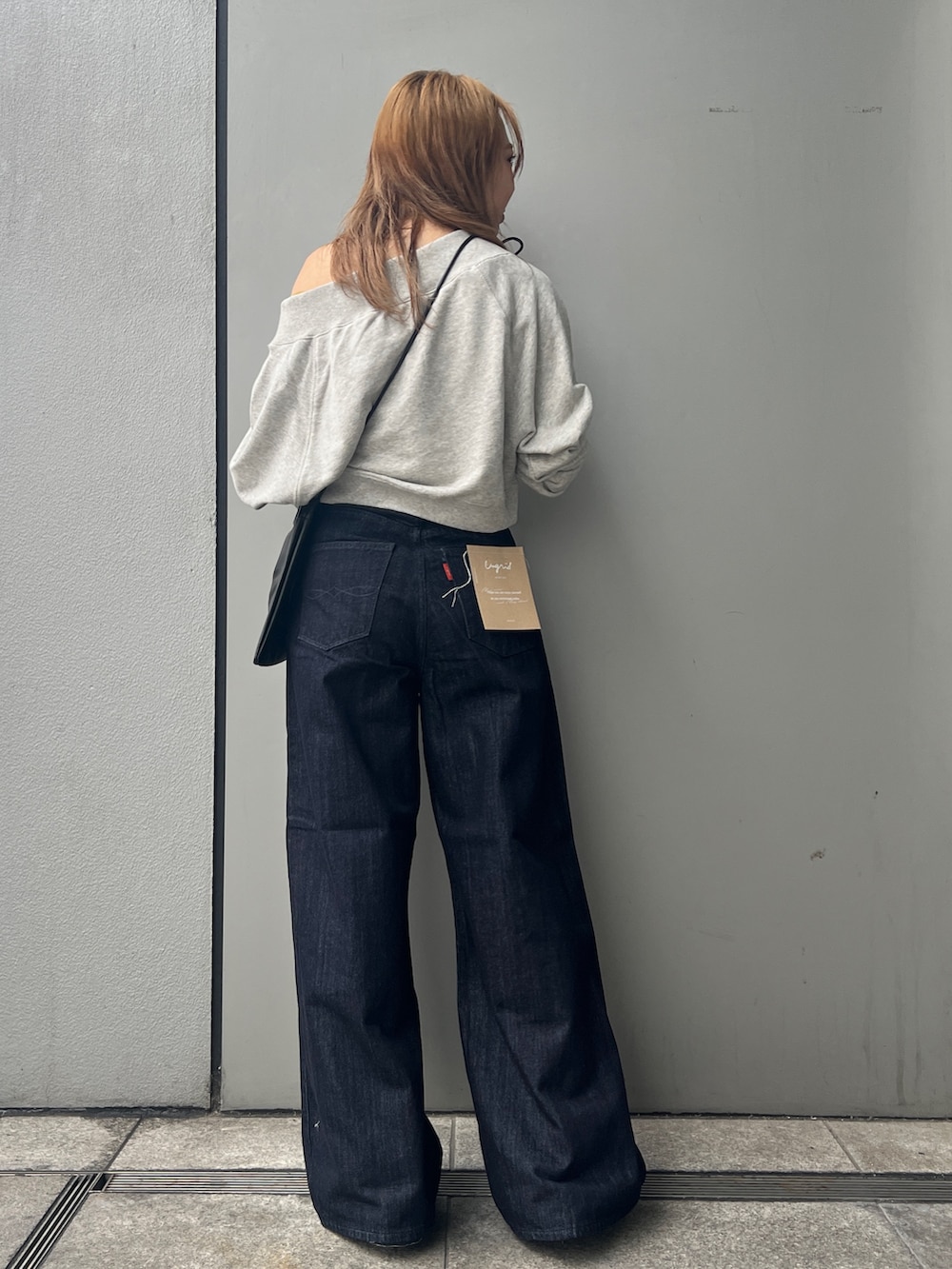 ブルー系のデニムパンツ、グレー系のスウェット、ブラック系のショルダーバッグを着用したレディースの秋コーディネートの3枚目の写真