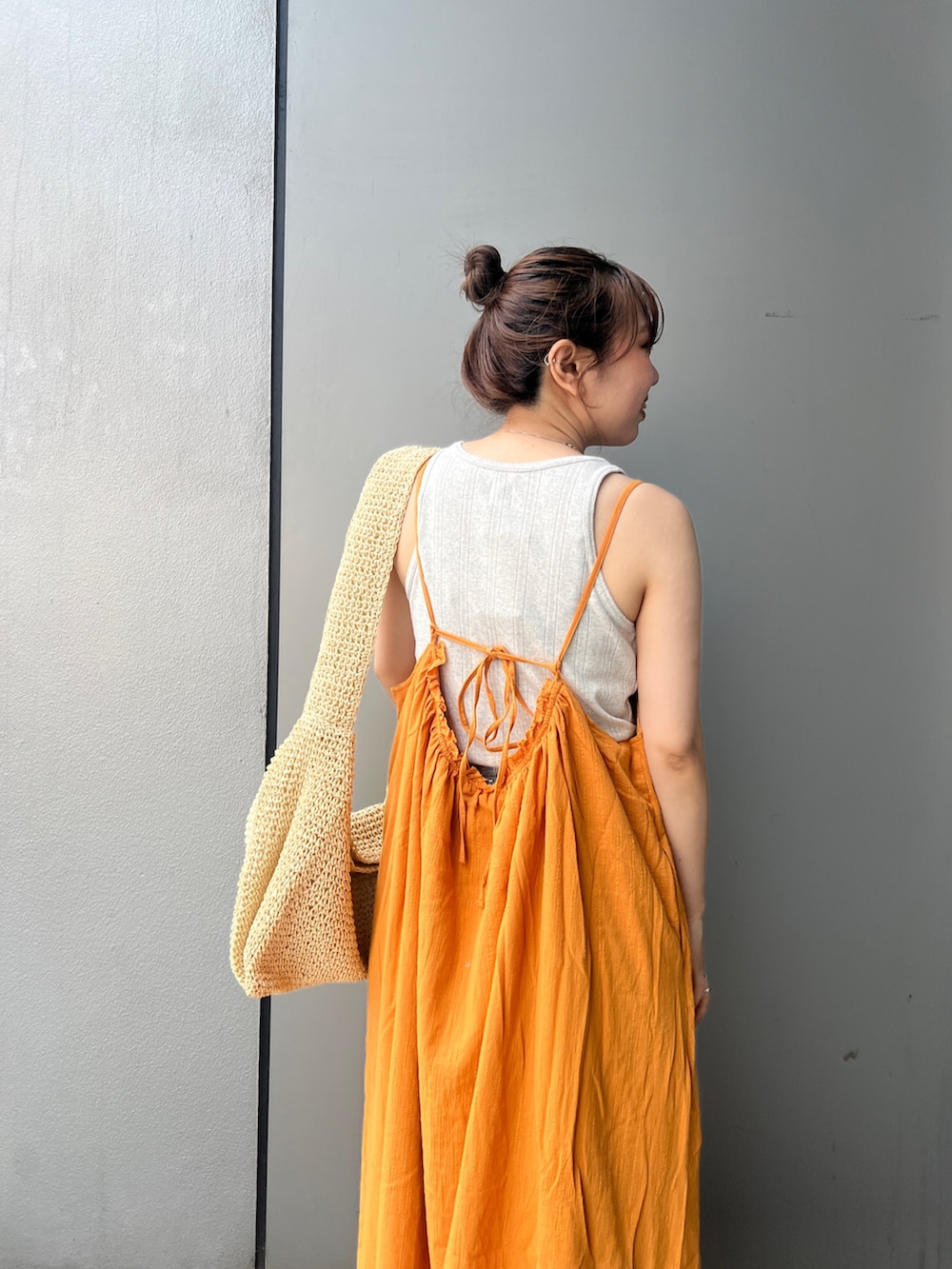 オレンジ系のワンピース、グレー系のタンクトップ、ベージュ系のショルダーバッグを着用したレディースの夏コーディネートの4枚目の写真