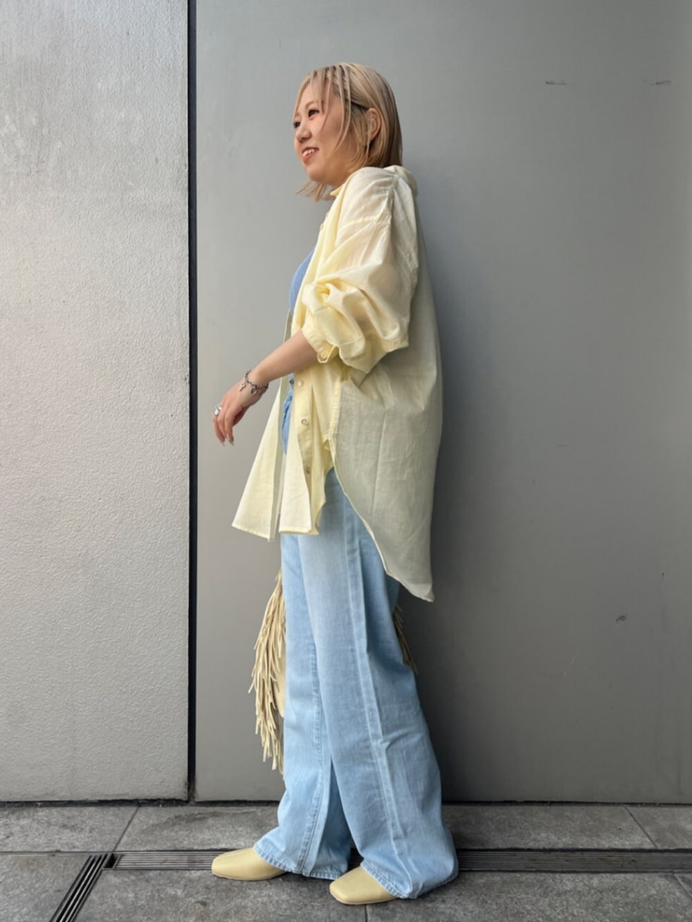 イエロー系のハンドバッグ、ブルー系のデニムパンツ、イエロー系のサンダルを着用したレディースの春コーディネートの3枚目の写真