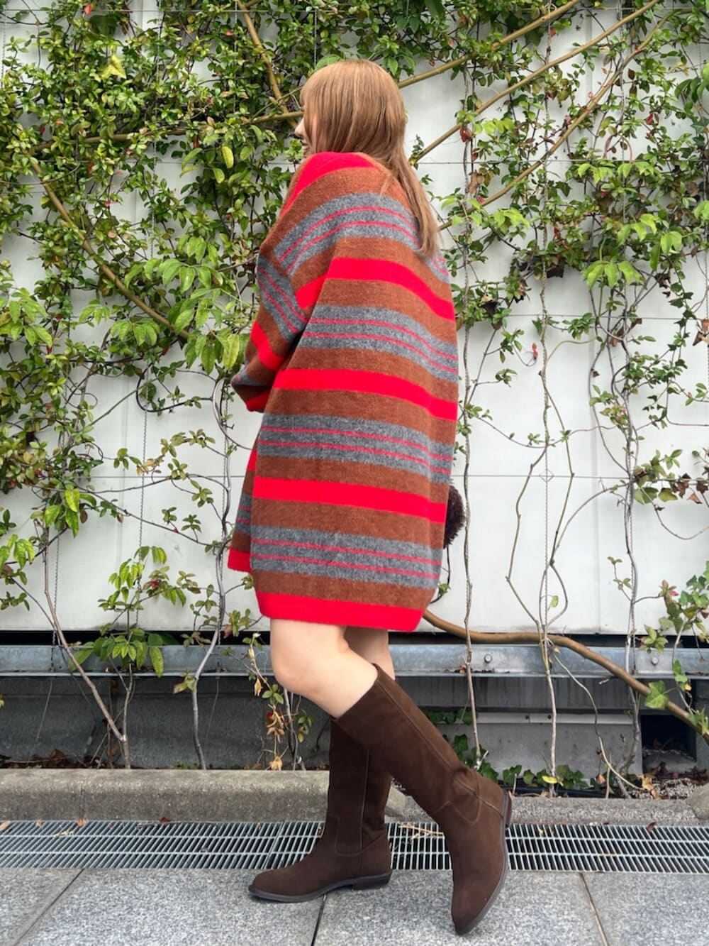 ブラウン系のハンドバッグ、レッド系のニット/セーター、ブラウン系のブーツを着用したレディースの秋コーディネートの3枚目の写真