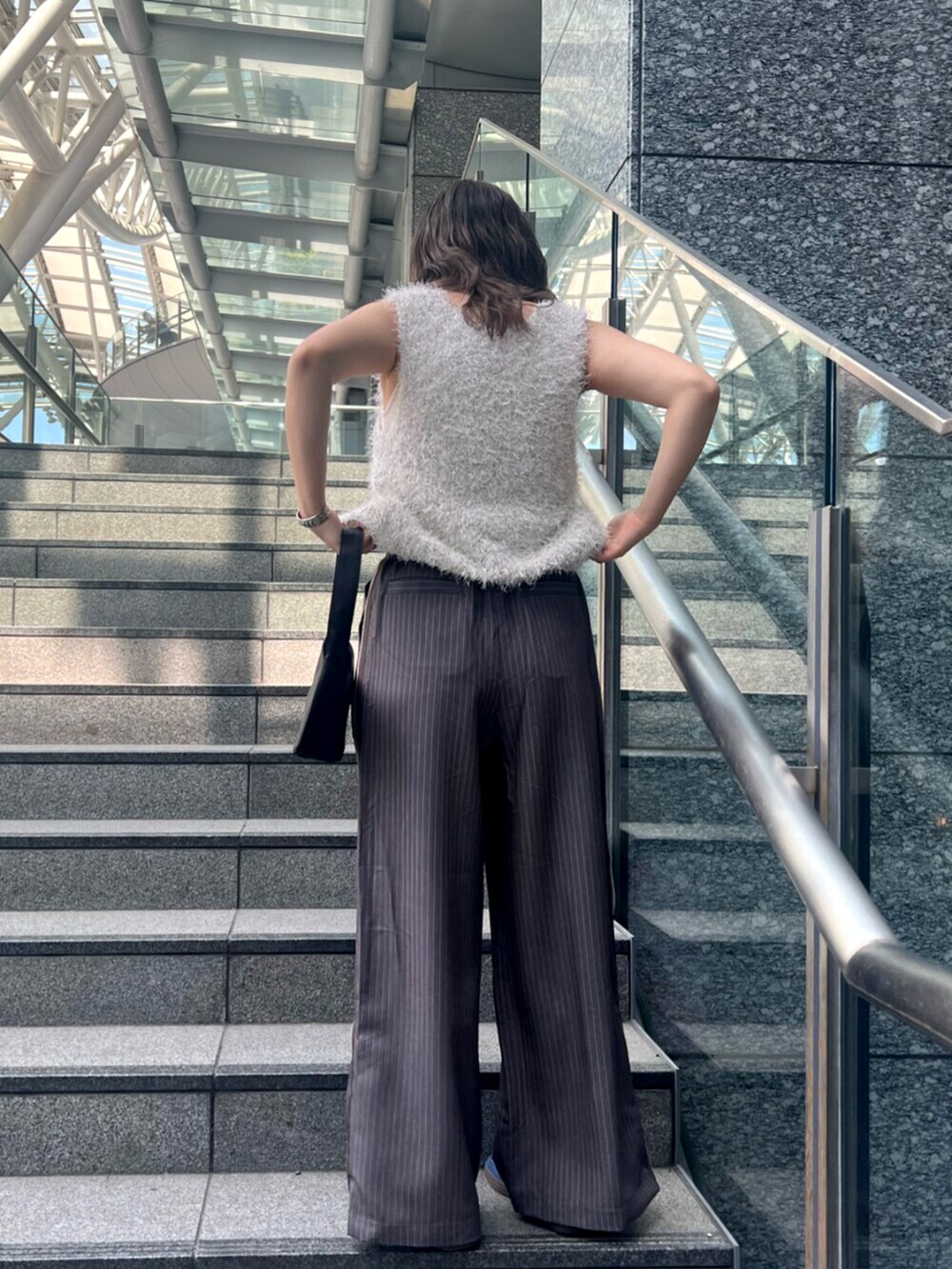 グレー系のその他パンツ、ホワイト系のベスト、ホワイト系のキャミソールを着用したレディースの春コーディネートの3枚目の写真