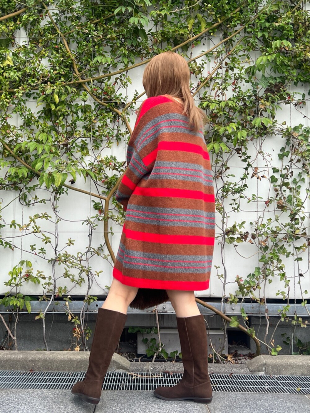 ブラウン系のハンドバッグ、レッド系のニット/セーター、ブラウン系のブーツを着用したレディースの秋コーディネートの4枚目の写真