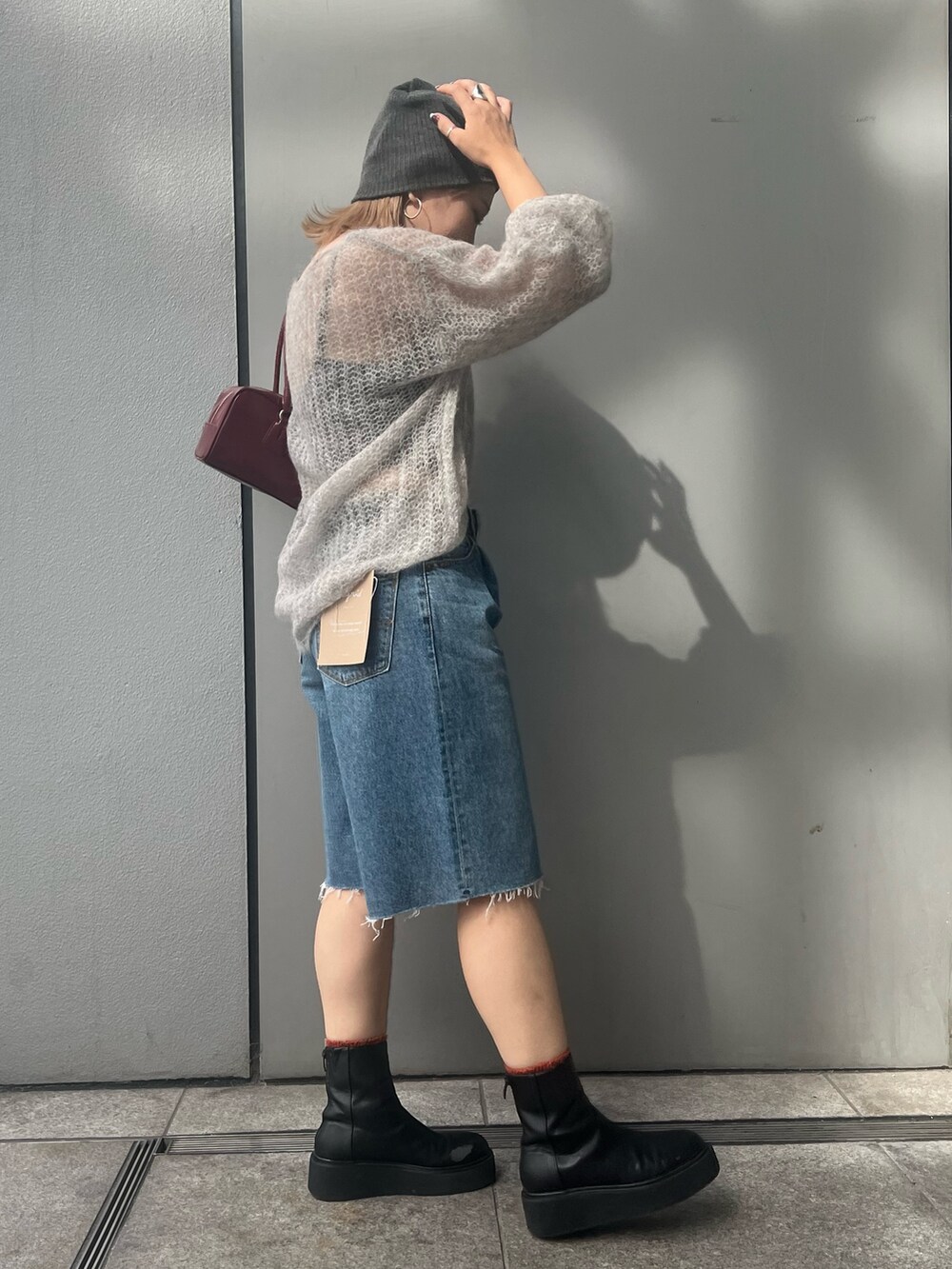 ブルー系のデニムパンツ、グレー系のニット/セーター、レッド系のハンドバッグを着用したレディースの秋コーディネートの4枚目の写真