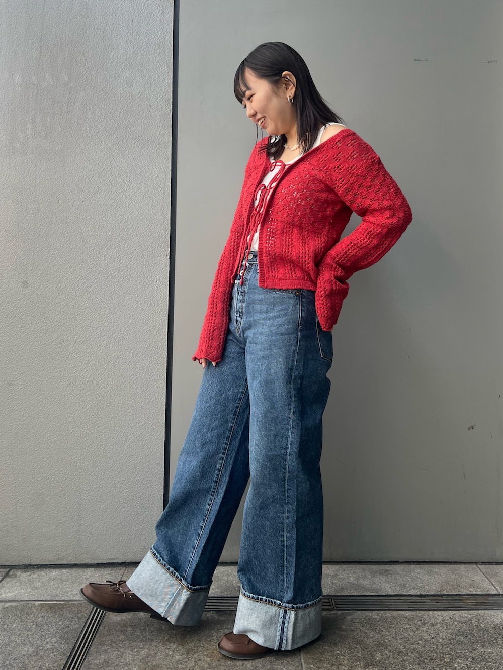 ブルー系のデニムパンツ、レッド系のカーディガン/ボレロ、ホワイト系のタンクトップを着用したレディースの冬コーディネートの3枚目の写真