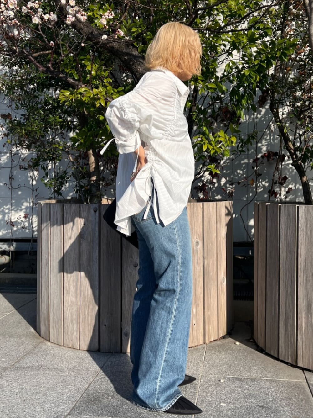 ブラック系のパンプス、ホワイト系のシャツ/ブラウス、ブルー系のデニムパンツを着用したレディースの春コーディネートの2枚目の写真