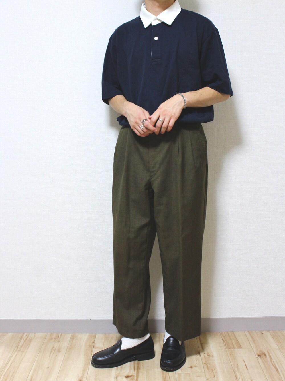 ブラウン系のスラックス、ブラック系のローファー、ブルー系のポロシャツを着用したメンズの夏コーディネートの2枚目の写真