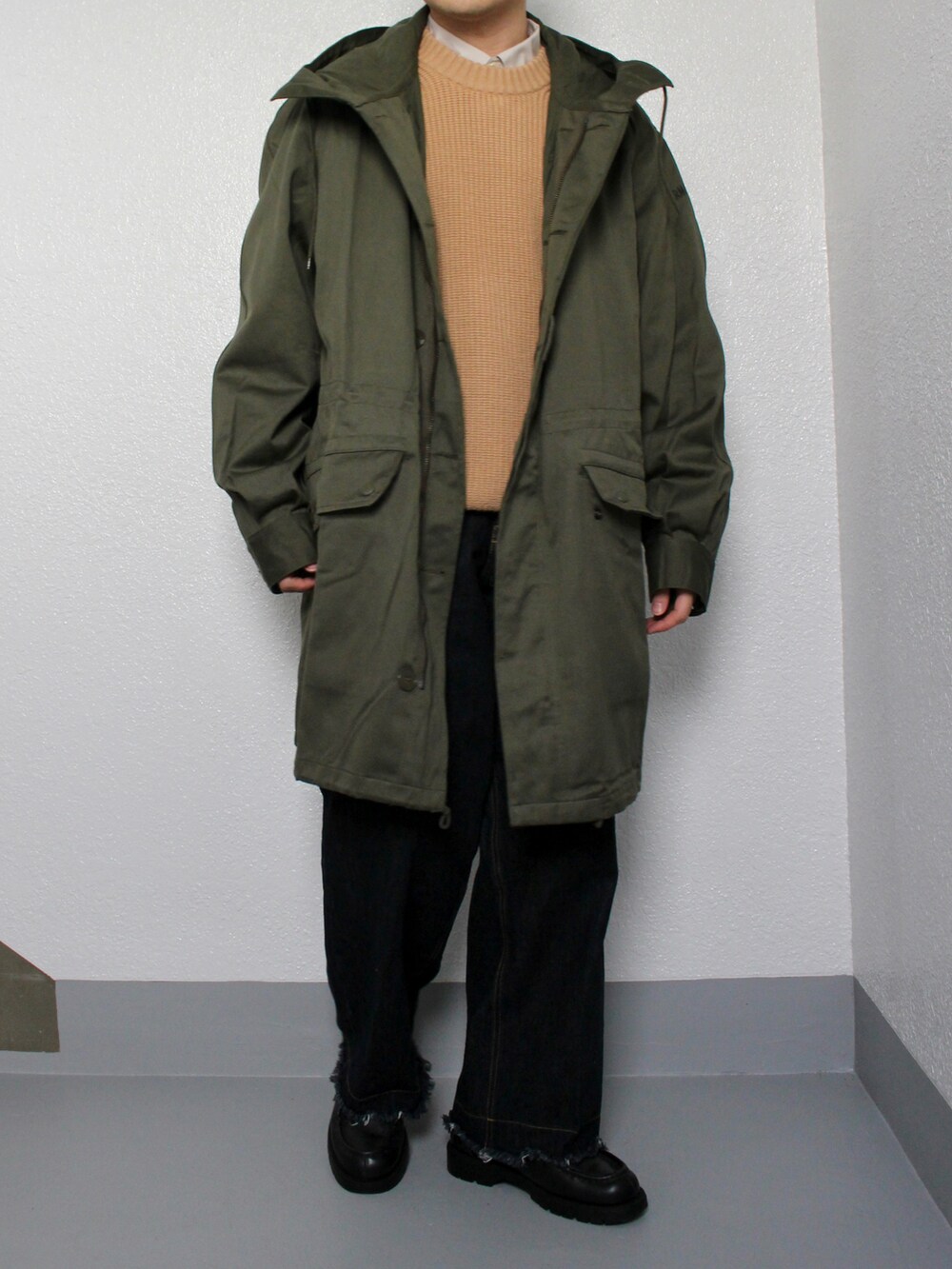 グリーン系のミリタリージャケット、ブルー系のデニムパンツ、ブラック系のドレスシューズを着用したメンズの冬コーディネートの2枚目の写真