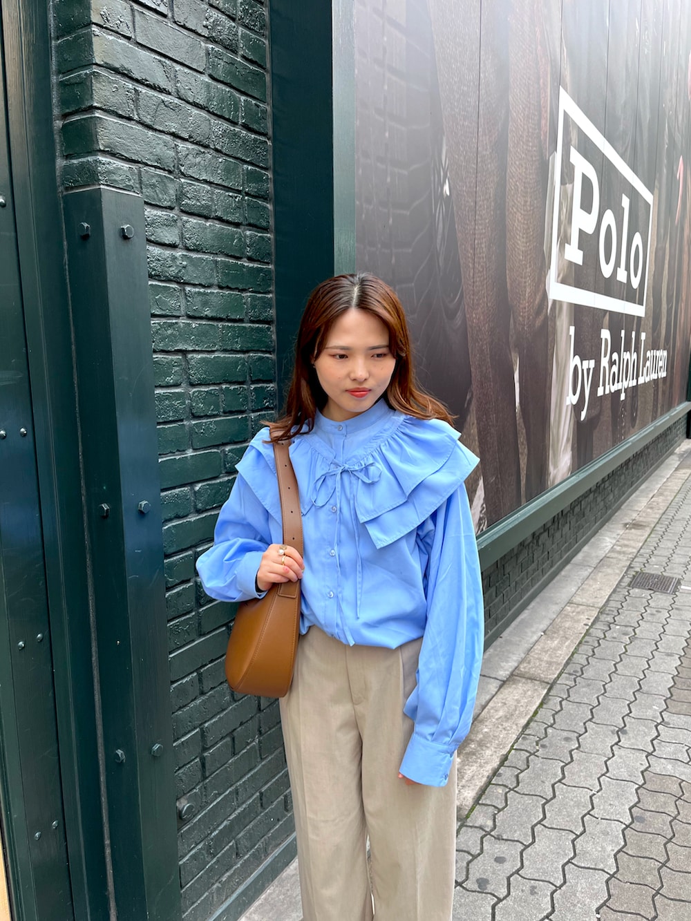 ブルー系のシャツ/ブラウス、ベージュ系のパンツ、ホワイト系のスニーカーを着用したレディースの秋コーディネートの2枚目の写真