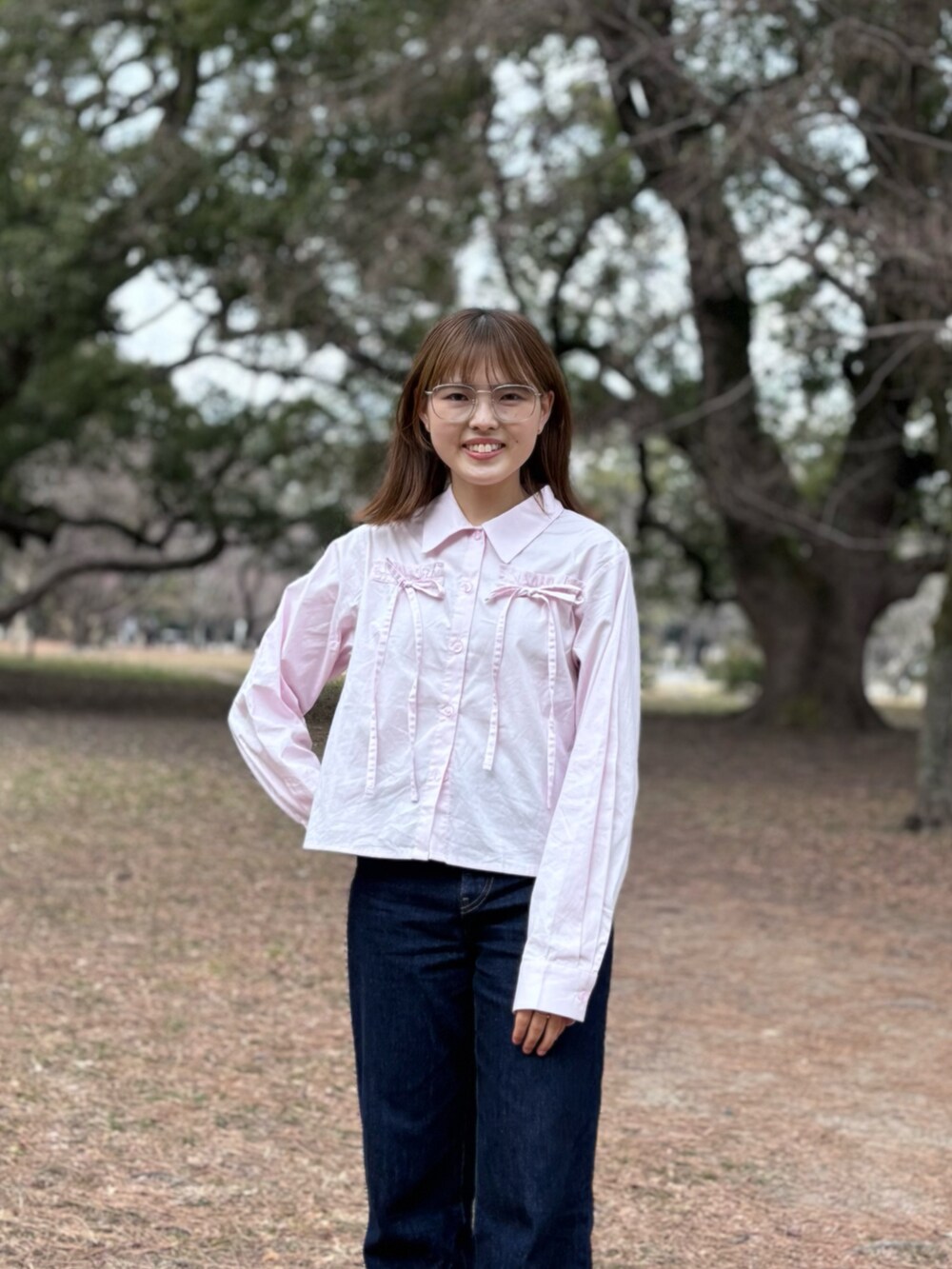 ピンク系のシャツ/ブラウス、ピンク系のスニーカー、ブルー系のデニムパンツを着用したレディースの春コーディネートの2枚目の写真