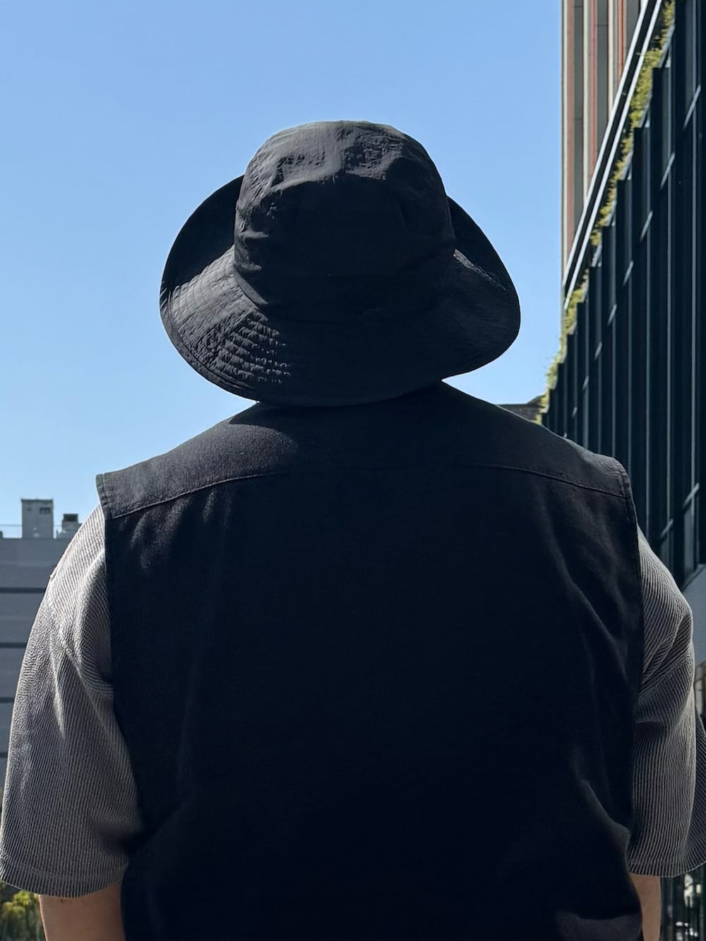 ブラック系のベスト、グレー系のTシャツ/カットソー、グリーン系のカーゴパンツを着用したメンズの春コーディネートの5枚目の写真