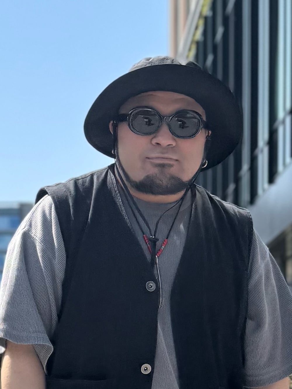 ブラック系のベスト、グレー系のTシャツ/カットソー、グリーン系のカーゴパンツを着用したメンズの春コーディネートの3枚目の写真