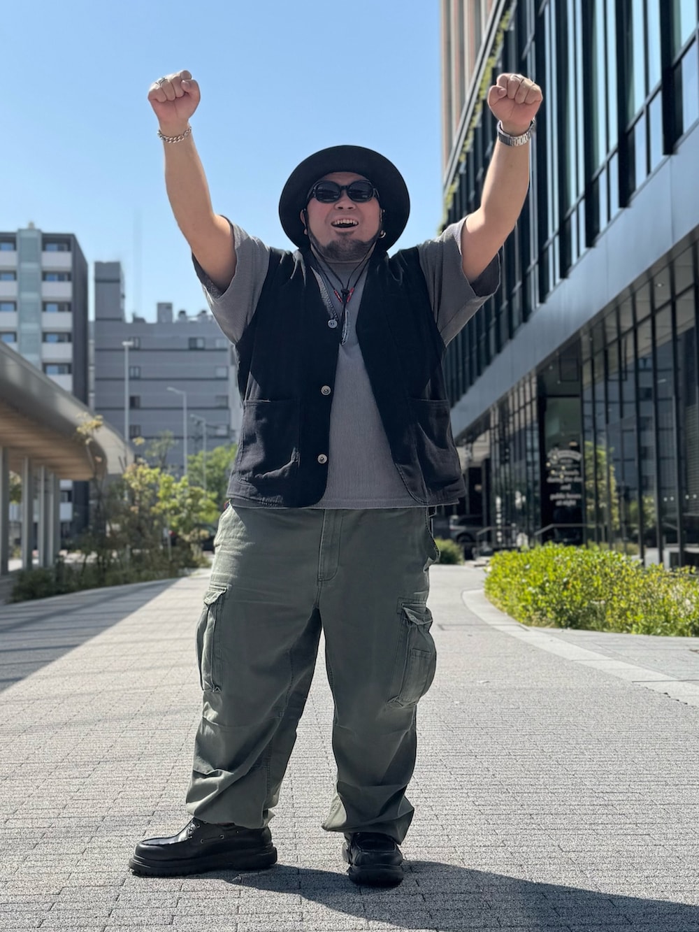 ブラック系のベスト、グレー系のTシャツ/カットソー、グリーン系のカーゴパンツを着用したメンズの春コーディネートの2枚目の写真