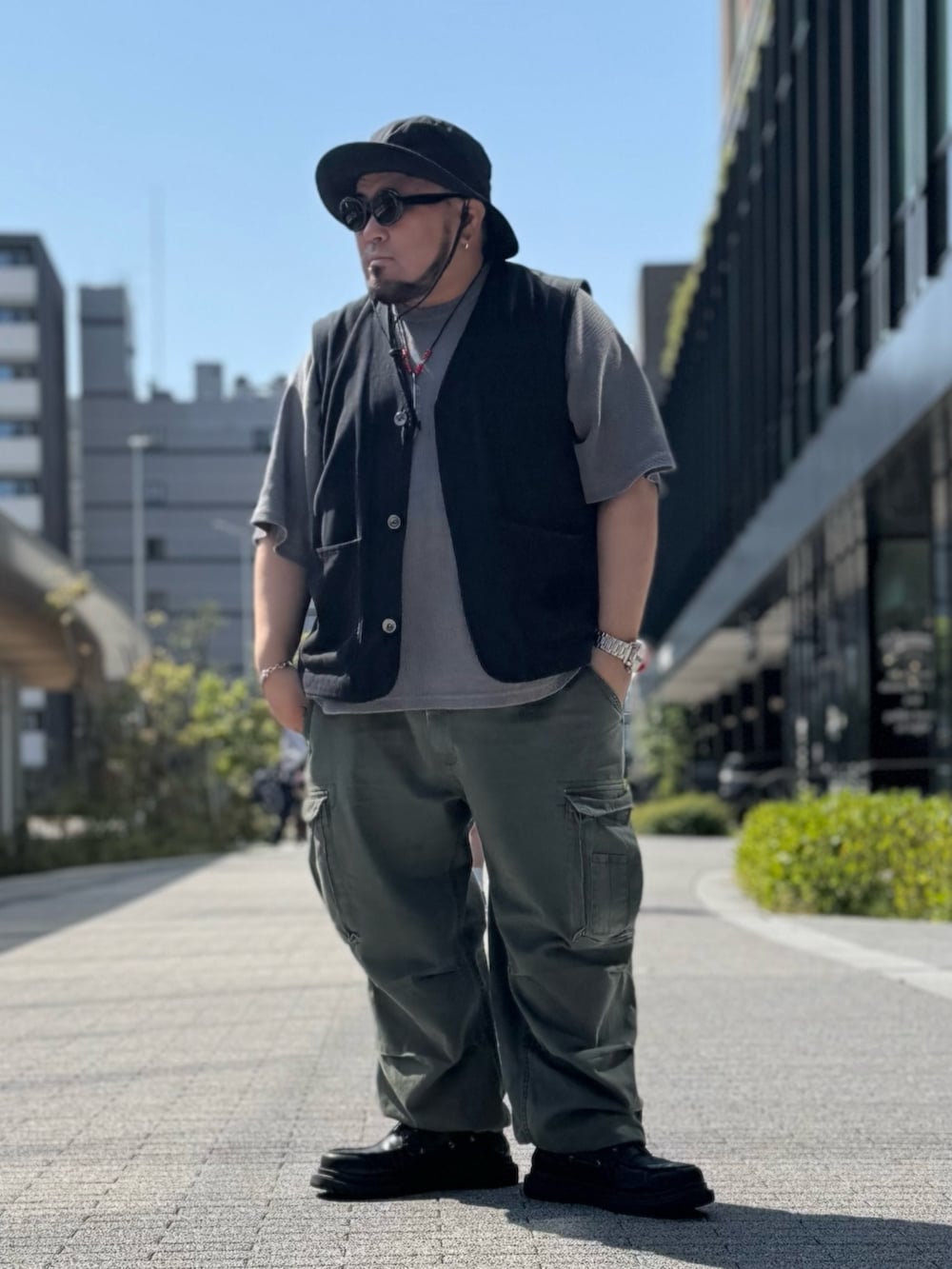 ブラック系のベスト、グレー系のTシャツ/カットソー、グリーン系のカーゴパンツを着用したメンズの春コーディネートの9枚目の写真