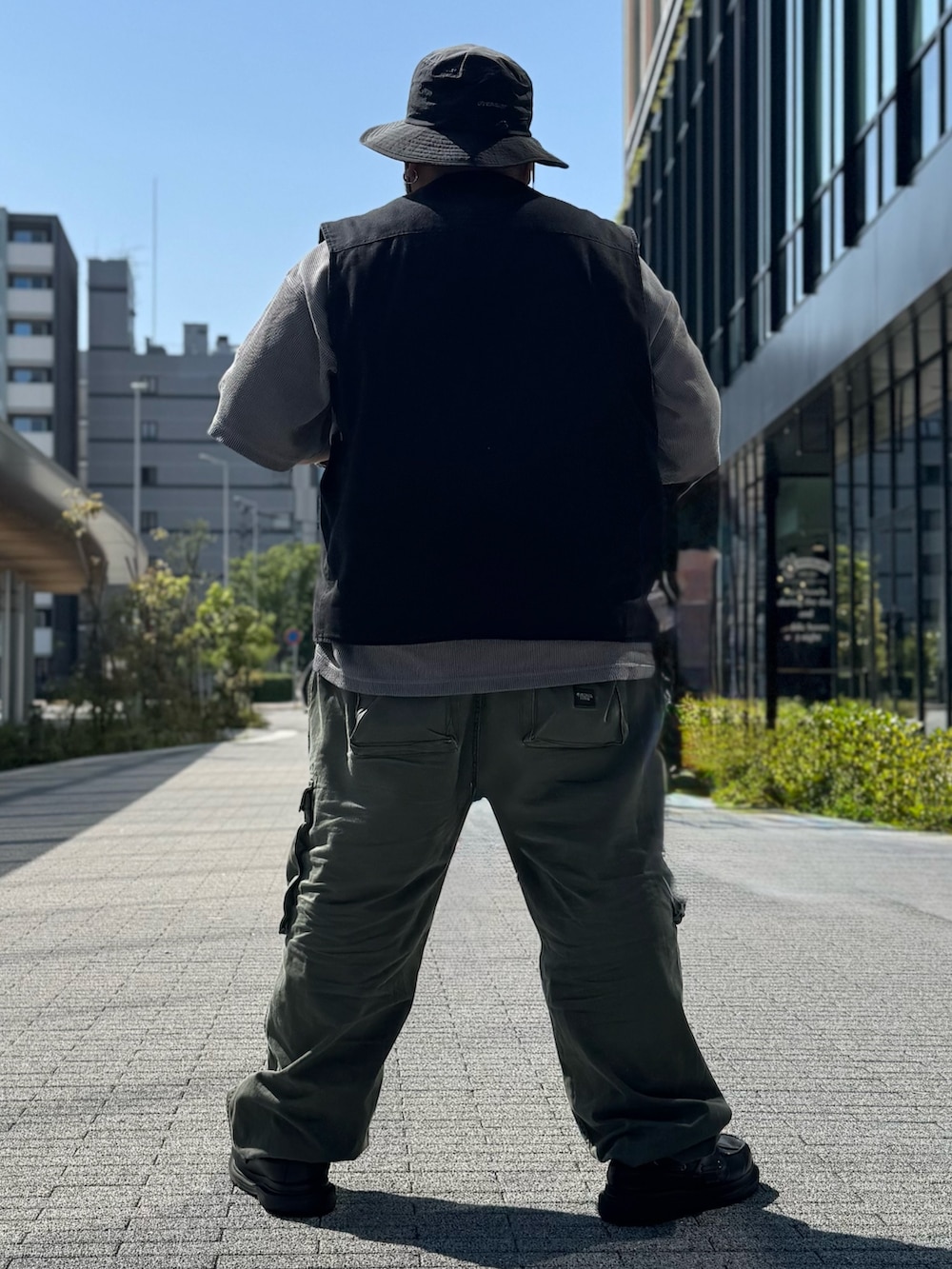 ブラック系のベスト、グレー系のTシャツ/カットソー、グリーン系のカーゴパンツを着用したメンズの春コーディネートの8枚目の写真