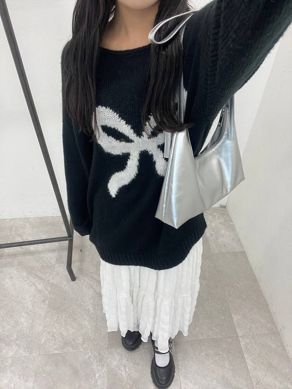 シルバー系のショルダーバッグ、ホワイト系のスカート、ブラック系のニット/セーターを着用したレディースの秋コーディネートの3枚目の写真