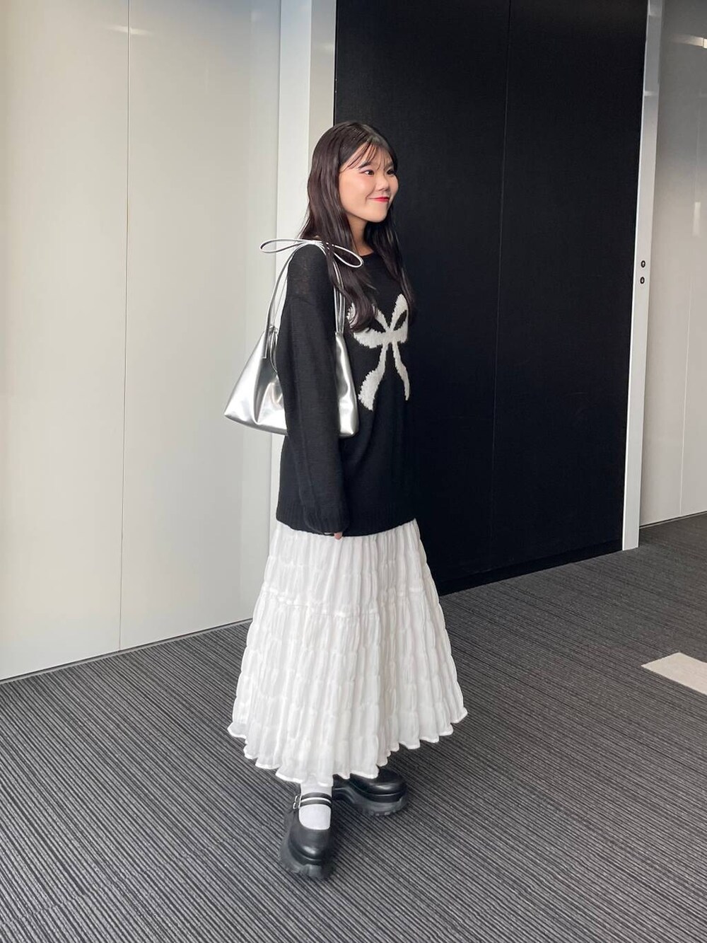シルバー系のショルダーバッグ、ホワイト系のスカート、ブラック系のニット/セーターを着用したレディースの秋コーディネートの4枚目の写真