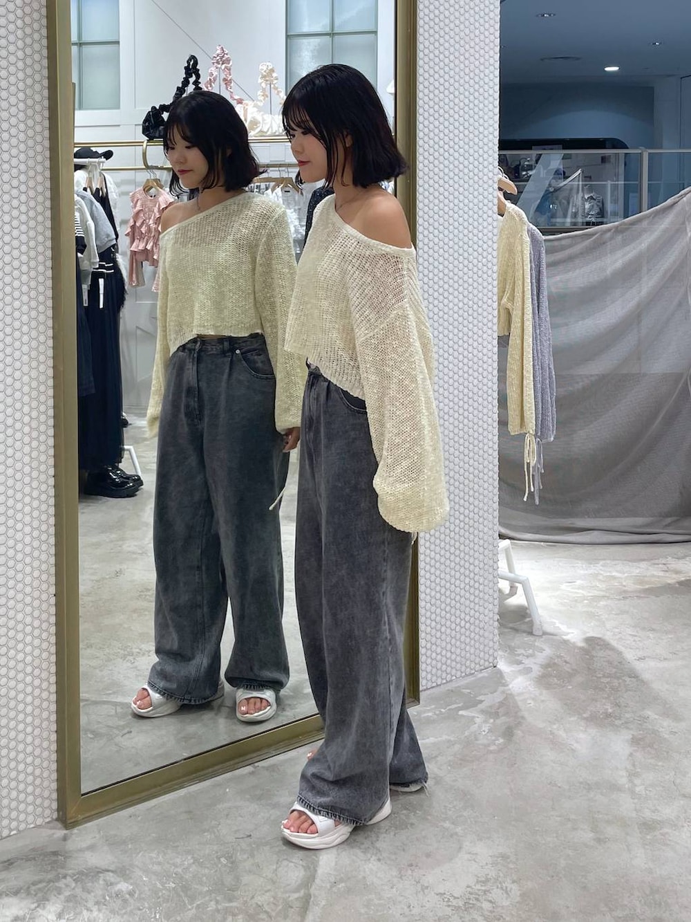 イエロー系のニット/セーター、グレー系のデニムパンツ、ホワイト系のサンダルを着用したレディースの秋コーディネートの2枚目の写真