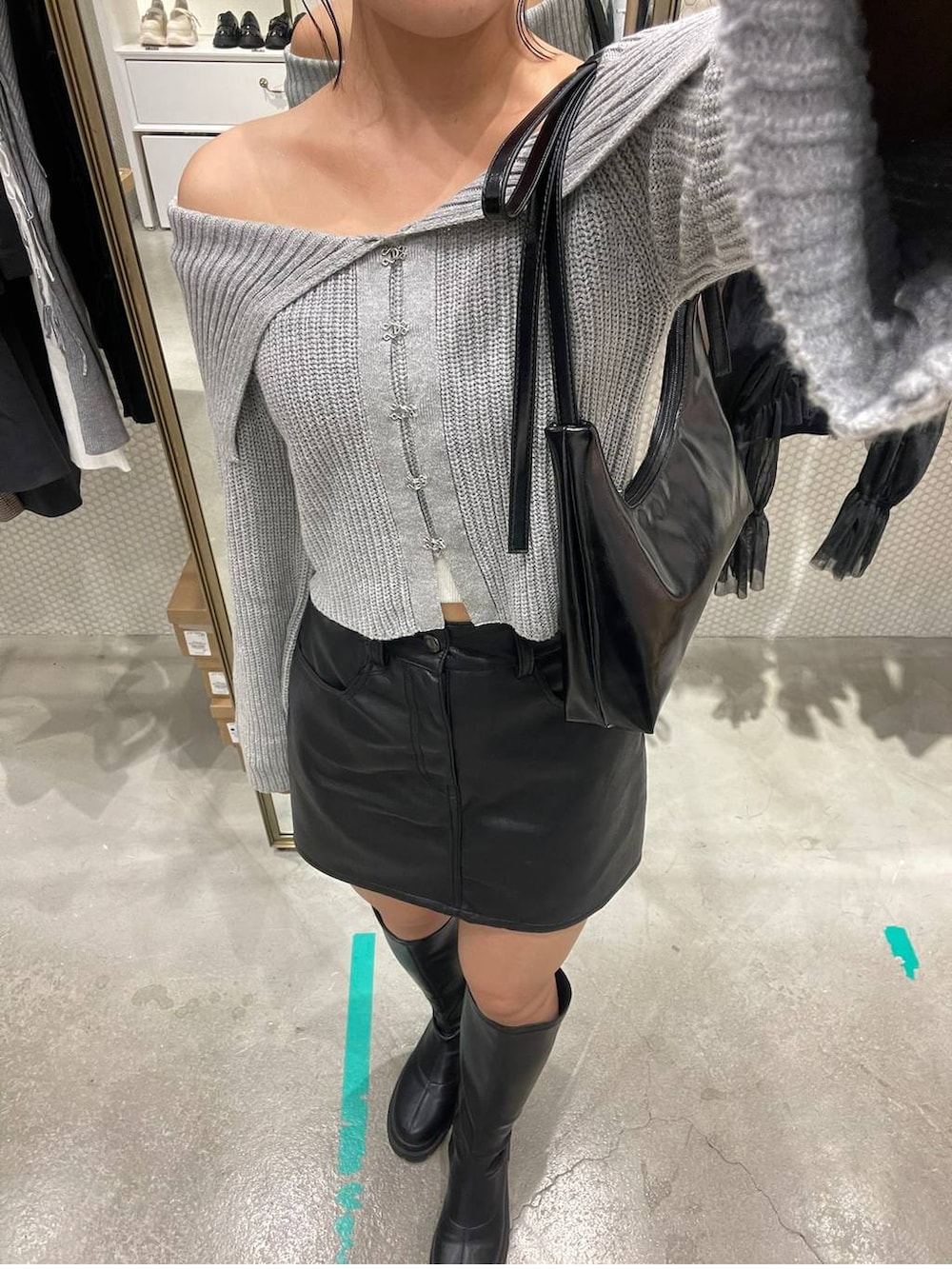 ブラック系のスカート、グレー系のニット/セーター、ブラック系のブーツを着用したレディースの秋コーディネートの3枚目の写真