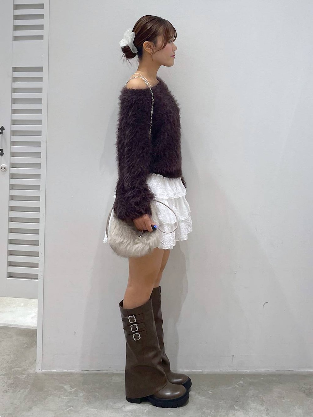 ブラウン系のブーツ、ホワイト系のスカート、ブラウン系のニット/セーターを着用したレディースの秋コーディネートの2枚目の写真