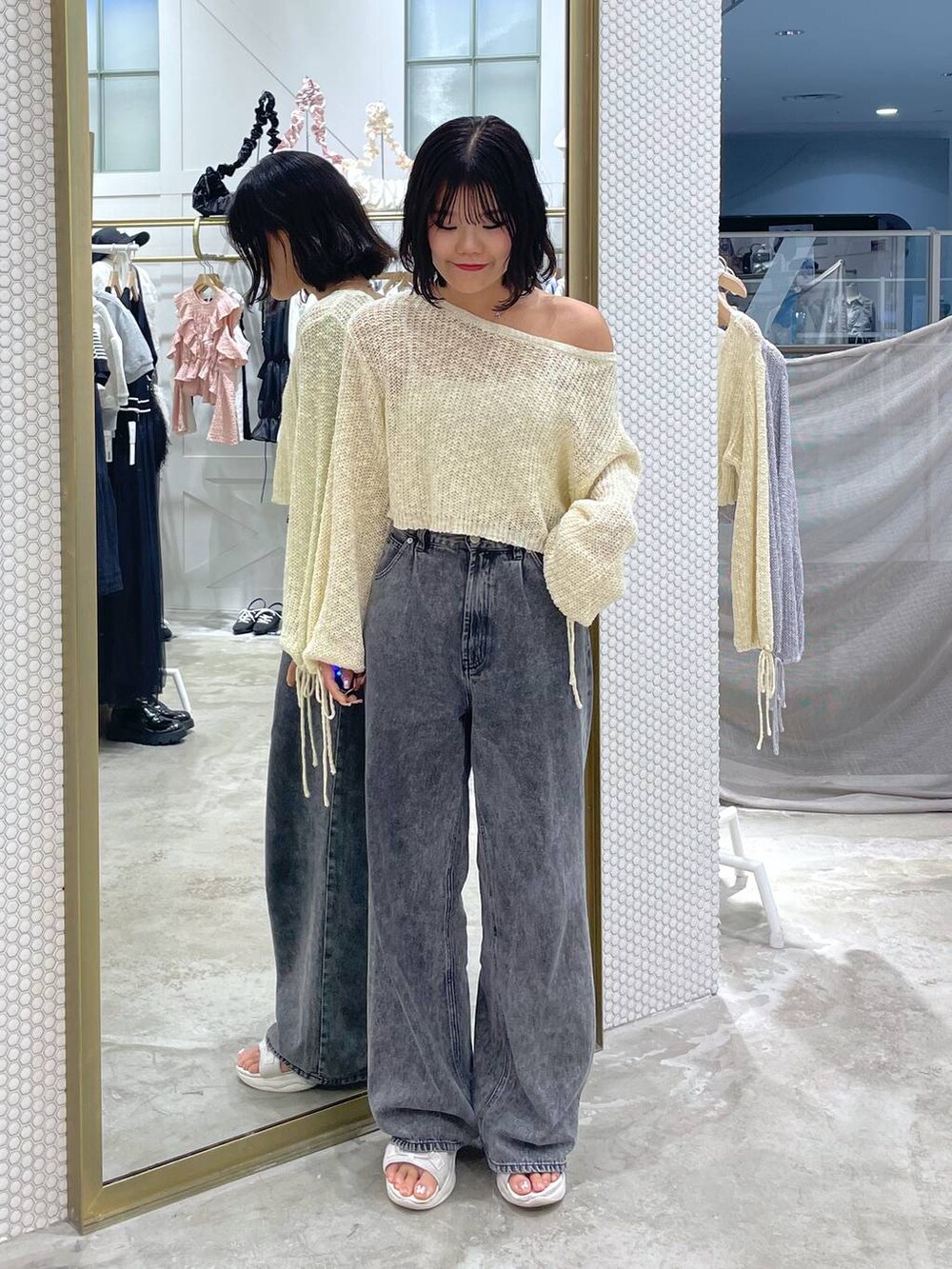 イエロー系のニット/セーター、グレー系のデニムパンツ、ホワイト系のサンダルを着用したレディースの秋コーディネートの3枚目の写真