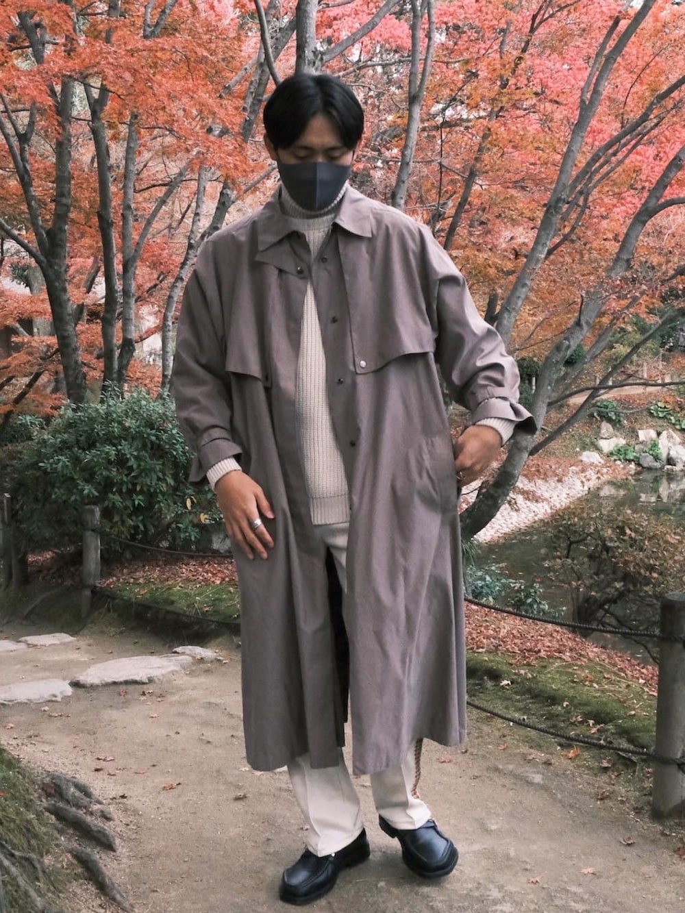 ベージュ系のステンカラーコート、ホワイト系のその他パンツ、ホワイト系のニット/セーターを着用したメンズの冬コーディネートの2枚目の写真