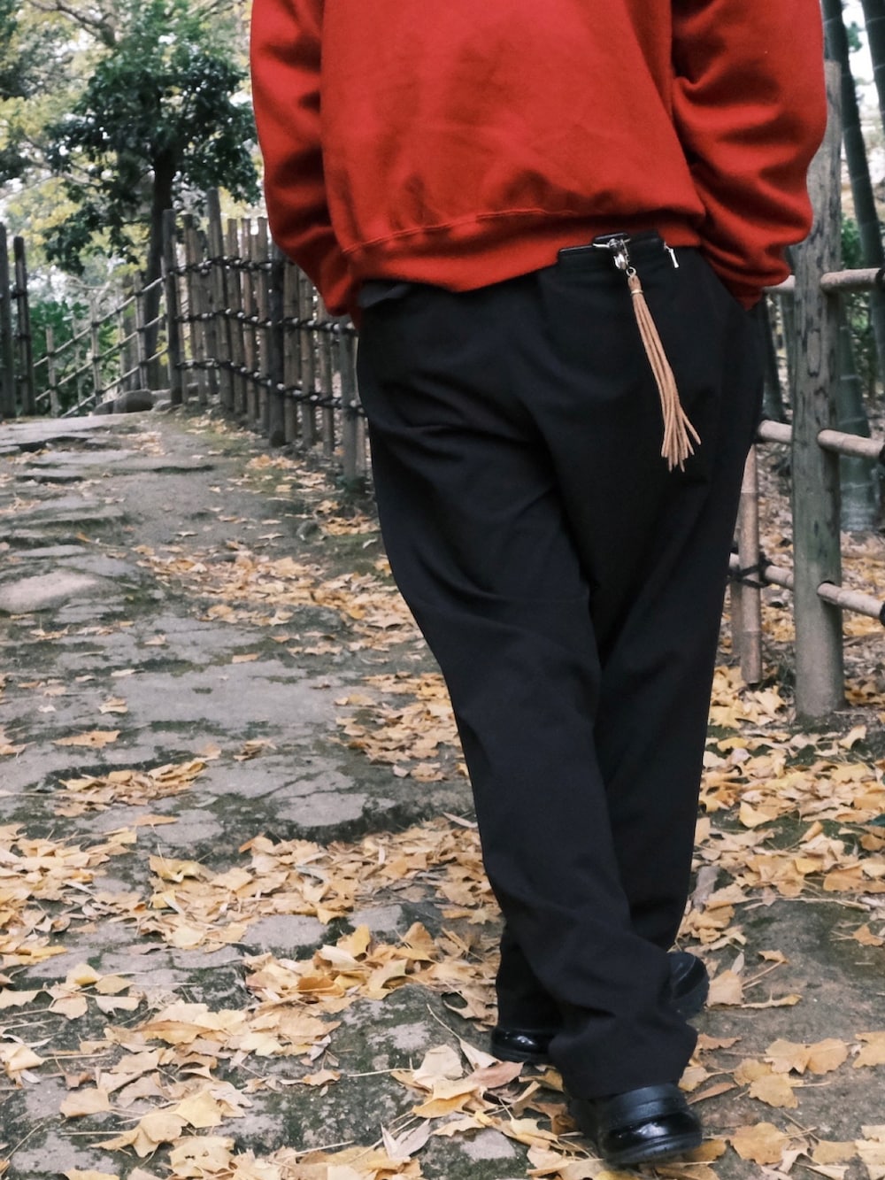 レッド系のスウェット、ブラック系のスラックス、ブラック系のスニーカーを着用したメンズの冬コーディネートの3枚目の写真