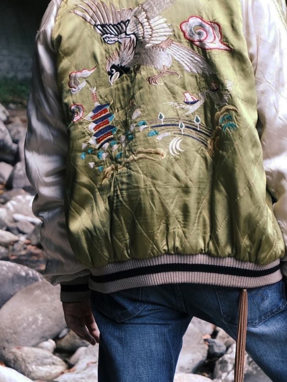 ブルー系のデニムパンツ、グリーン系のスニーカー、イエロー系のスカジャンを着用したメンズの秋コーディネートの3枚目の写真