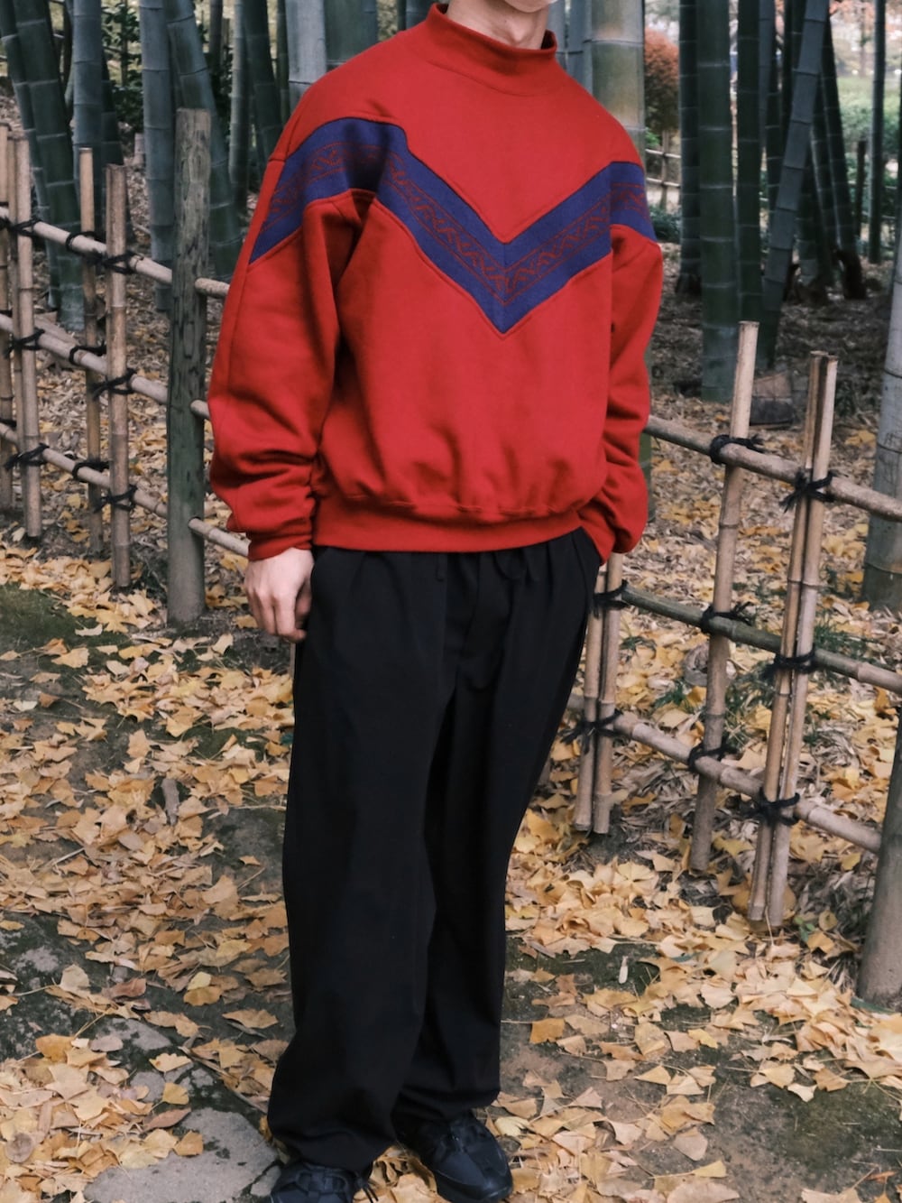 レッド系のスウェット、ブラック系のスラックス、ブラック系のスニーカーを着用したメンズの冬コーディネートの2枚目の写真