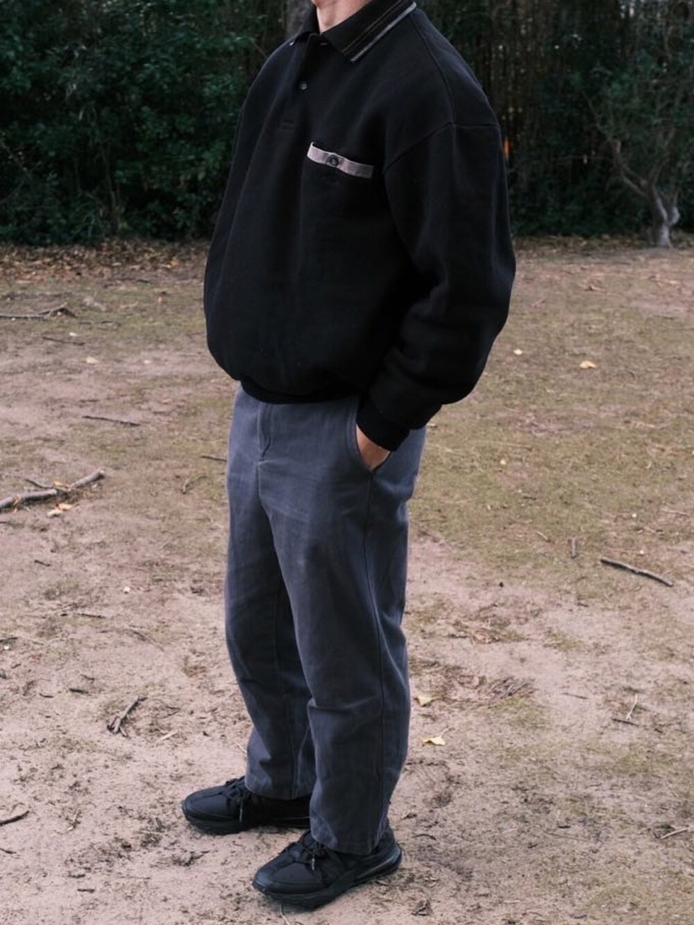 ブラック系のポロシャツ、グレー系のその他パンツ、ブラック系のスニーカーを着用したメンズの冬コーディネートの2枚目の写真