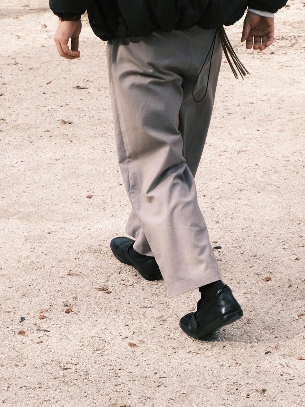 グレー系のスラックス、ブラック系のローファー、ホワイト系のスウェットを着用したメンズの冬コーディネートの2枚目の写真