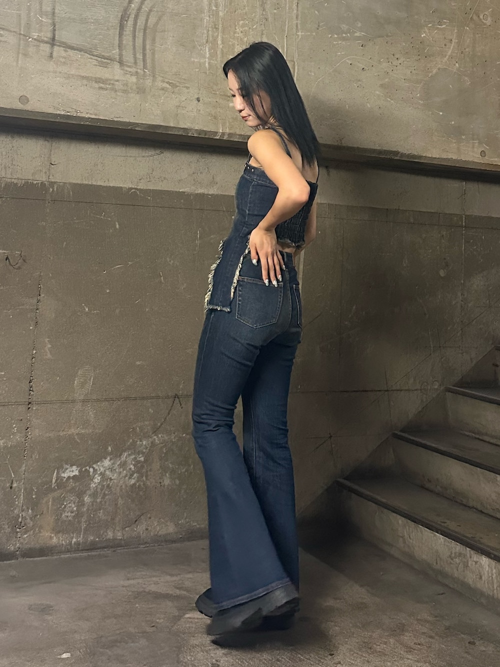 ブルー系のキャミソール、ブルー系のデニムパンツ、ブラック系のブーツを着用したレディースの夏コーディネートの4枚目の写真