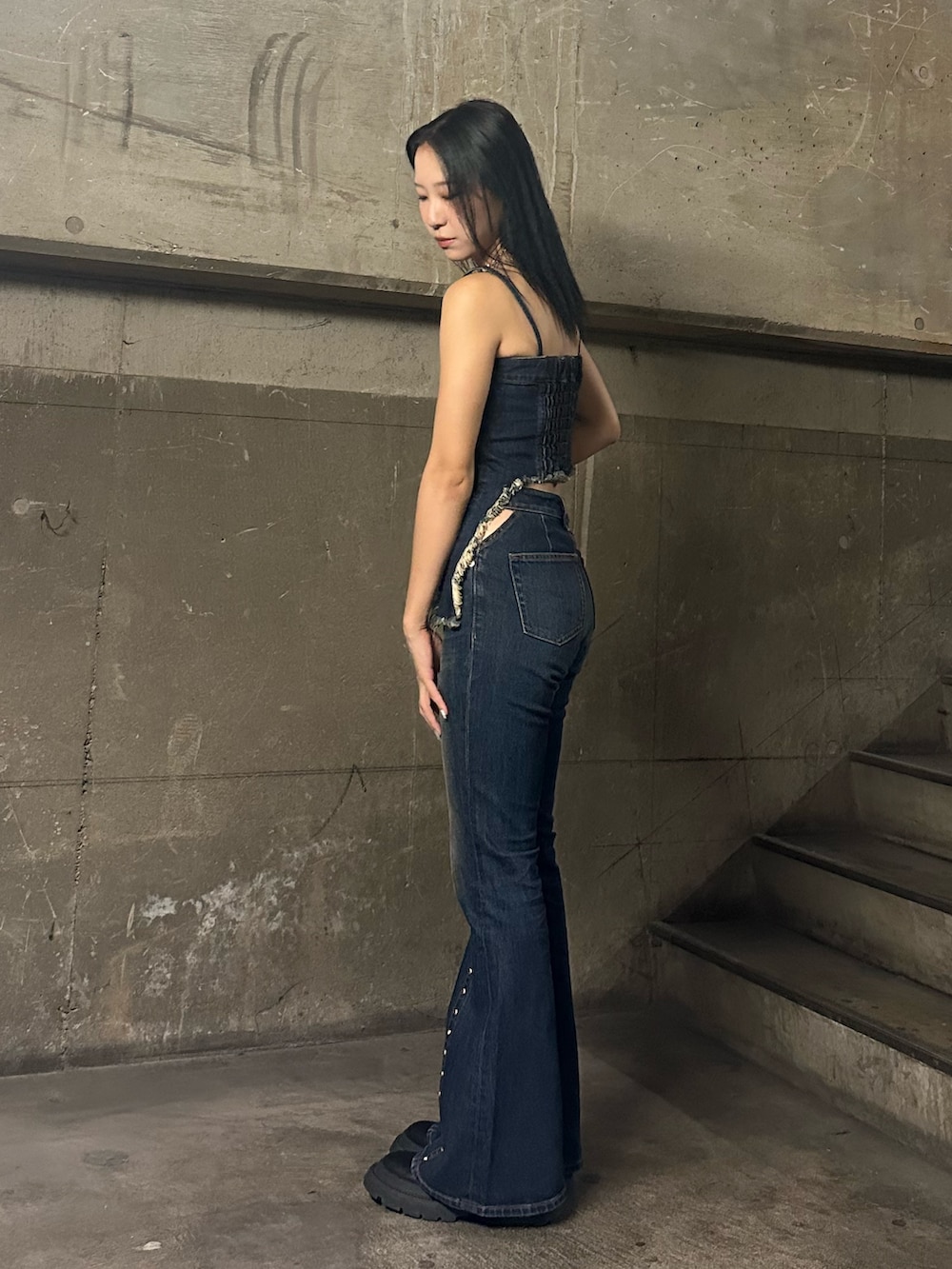 ブルー系のキャミソール、ブルー系のデニムパンツ、ブラック系のブーツを着用したレディースの夏コーディネートの2枚目の写真