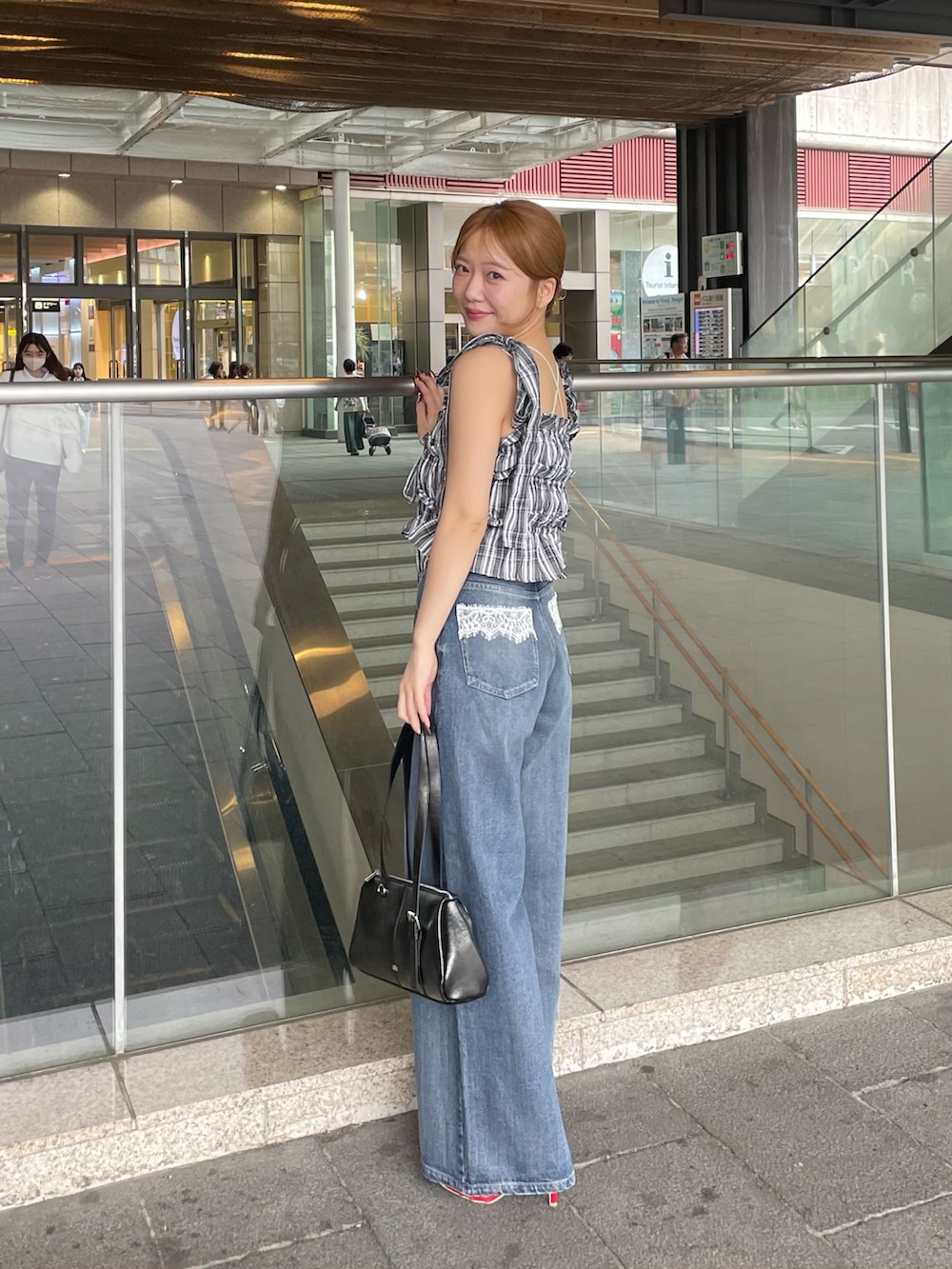 ブラック系のワンピース、ブルー系のデニムパンツ、ブラック系のボストンバッグを着用したレディースの春コーディネートの2枚目の写真