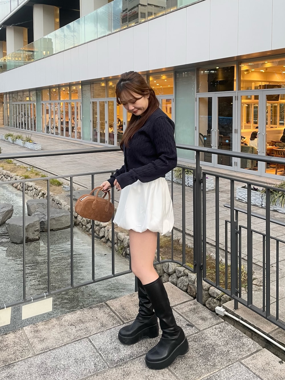 ブルー系のカーディガン/ボレロ、ホワイト系のスカート、ベージュ系のボストンバッグを着用したレディースの春コーディネートの6枚目の写真