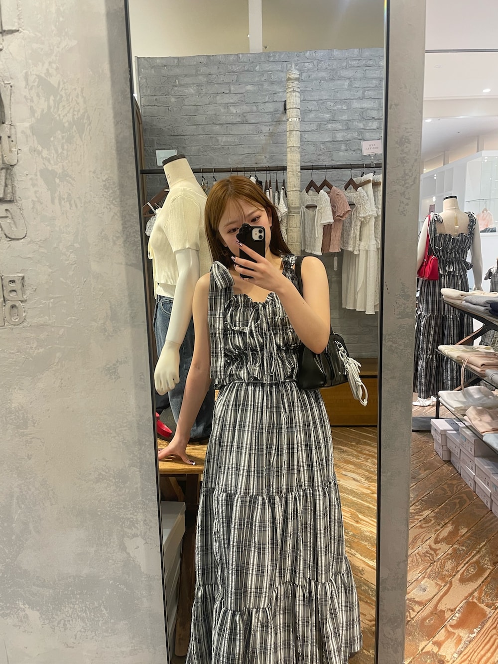 ブラック系のワンピース、ブルー系のデニムパンツ、ブラック系のボストンバッグを着用したレディースの春コーディネートの8枚目の写真